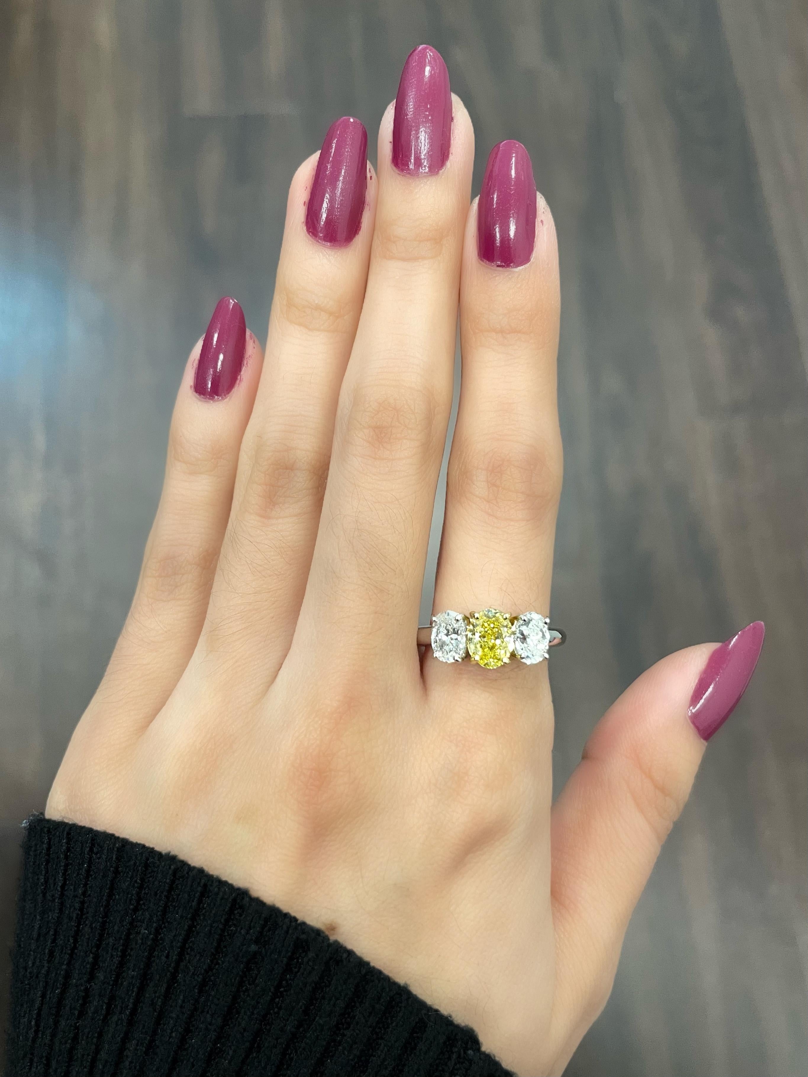 This stunning 2.21-carat three-stone yellow and white diamond ring is the perfect addition to any jewelry collection. The center stone is a beautiful natural yellow diamond weighing .96 Fancy intense yellow accompanied by GIA.  The ring is