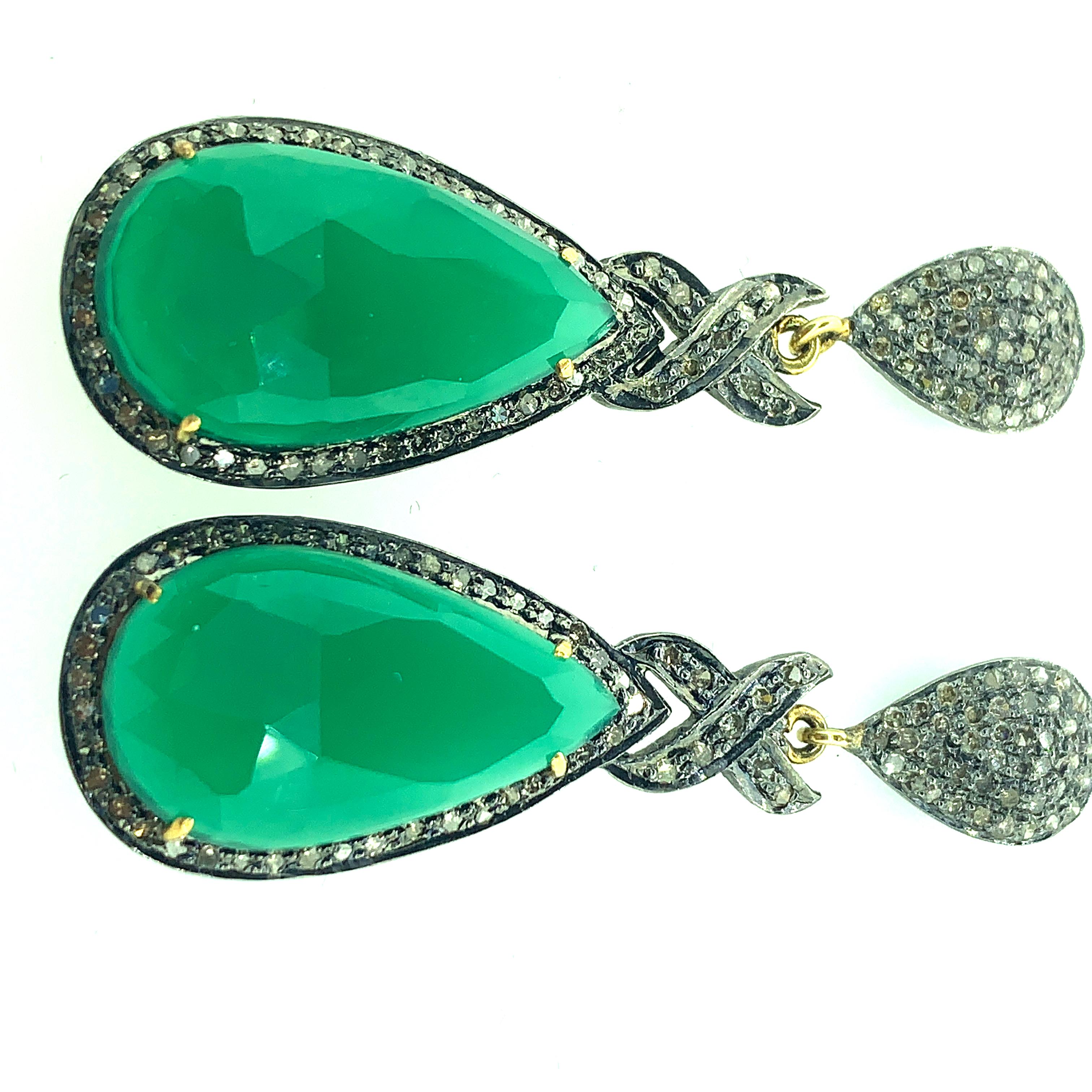 Beautifully crafted in Sterling, silver this green onyx earrings are sure to draw the eyes. This pear- shaped green onyx , set in prongs within a glistening champagne diamond halo, fascinates with its intense color. X- cross pattern and drop pave