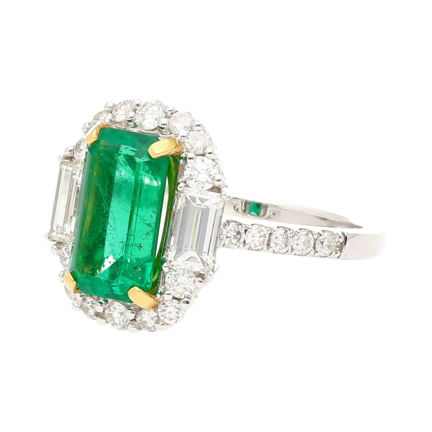 2.22 carat natural Colombian Emerald and Diamond Ring. Centering a lustrous emerald-cut emerald, measuring 10.3 x 6 MM, a desirable elongated shape that gracefully enhances the length of the finger.

The emerald is flanked by two baguette-cut