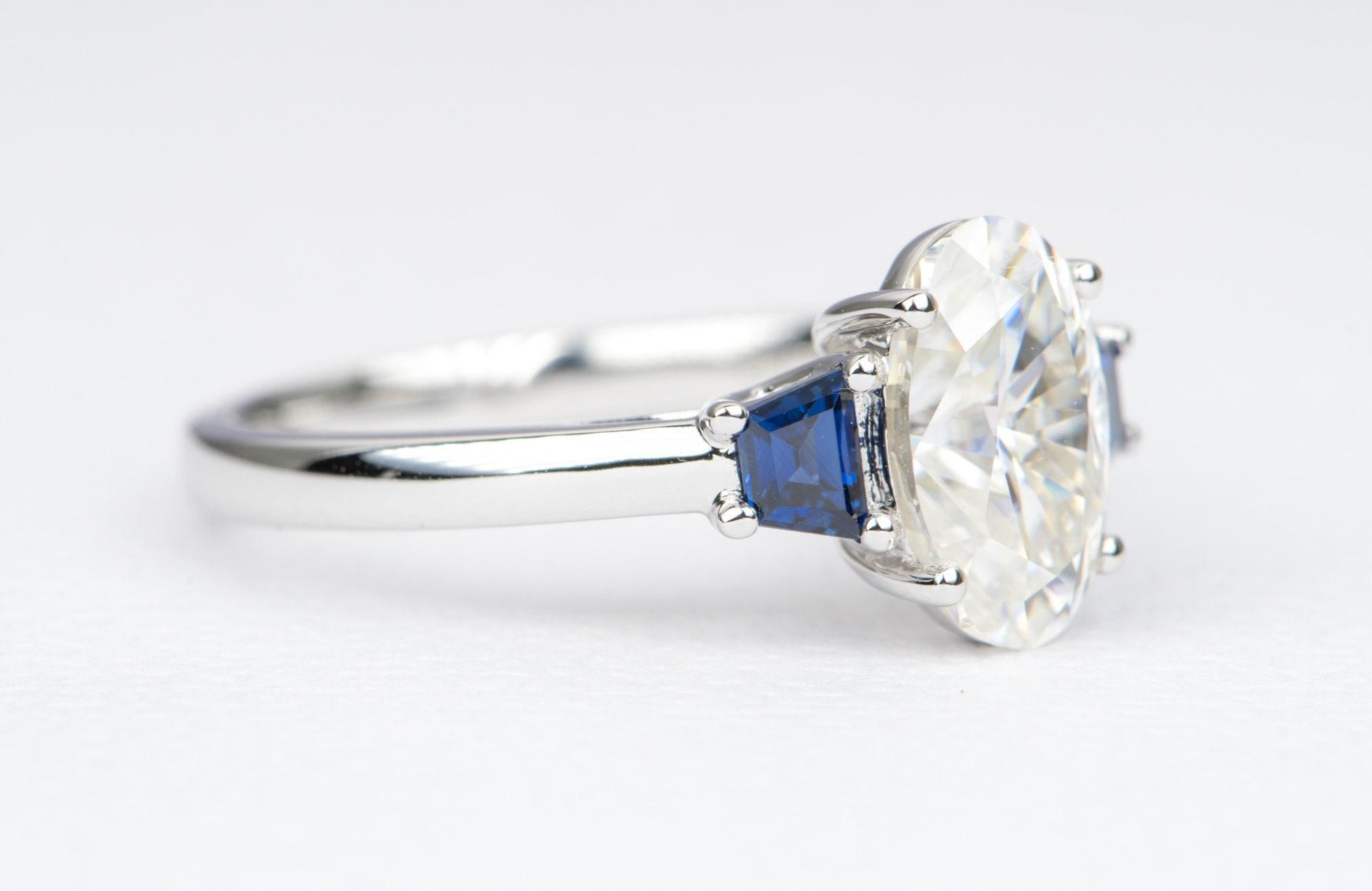 â™¥  A solid 14k white gold ring set with a elongated oval moissanite, flanked with trapezoid-shaped teal blue sapphire sides and a trellis-style open gallery to accent the center stone
â™¥  The overall setting measures 13mm in width, 10mm in