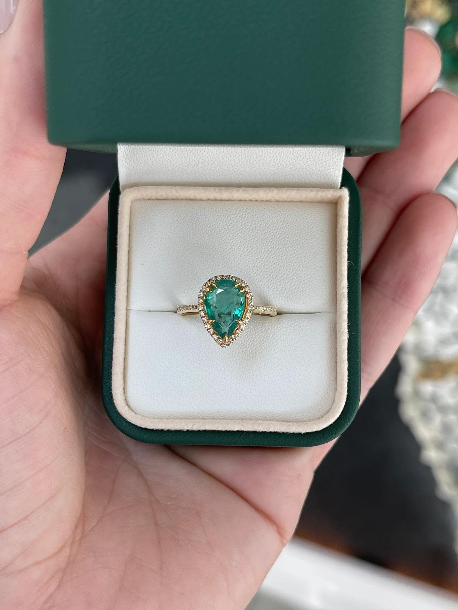 A ravishing emerald and diamond halo right-hand/engagement ring. This striking piece features a stunning pear-cut emerald from the natural origin of Zambia. The gemstone displays an alluring bluish-green hue with its natural medium green color. Very