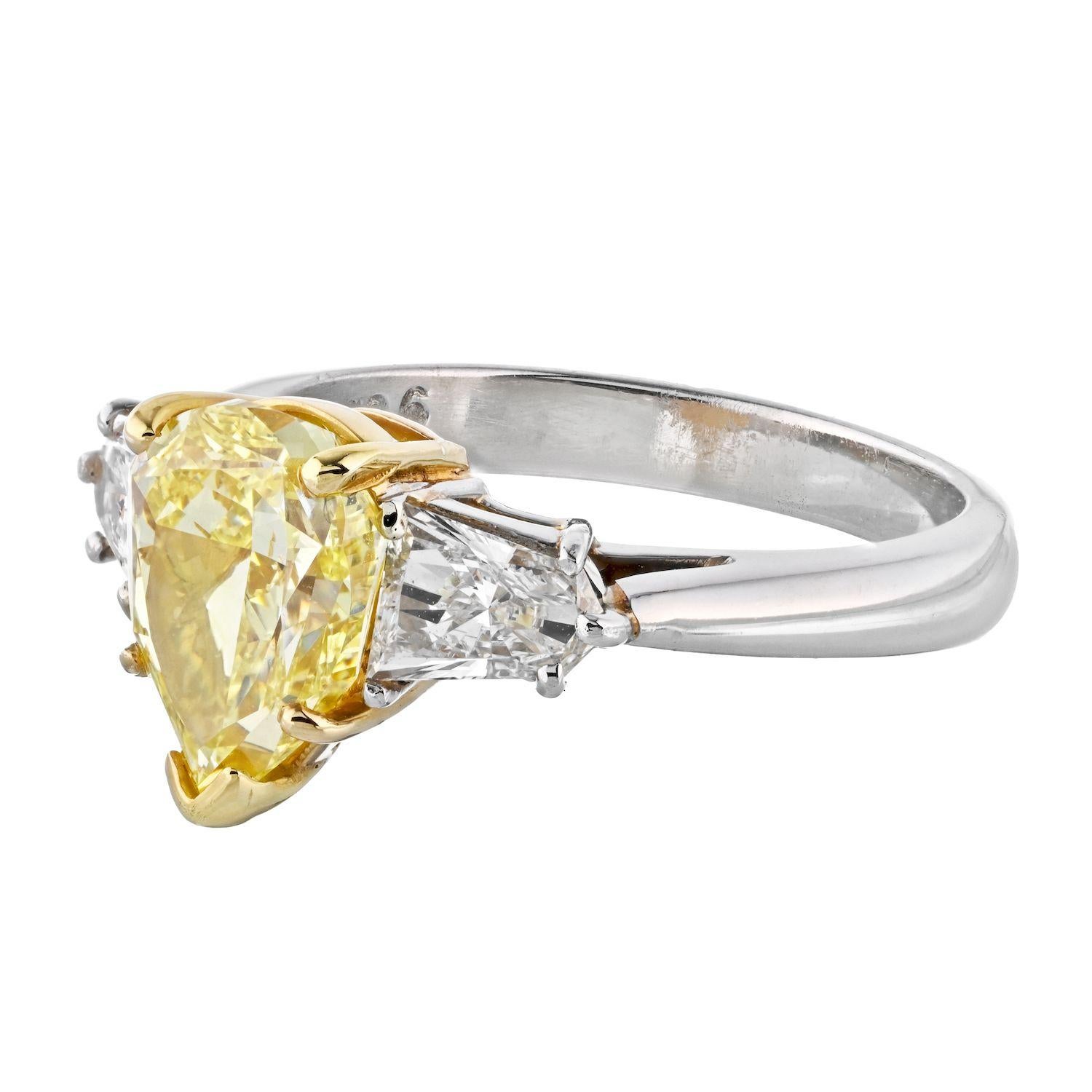 Three stone fancy yellow diamond engagement ring crafted in platinum and 18k yellow gold. Mounted with a 2.24 carat Pear cut natural fancy yellow intense color, VS1 clarity, certified GIA diamond. Side diamonds are natural white diamonds cut in a