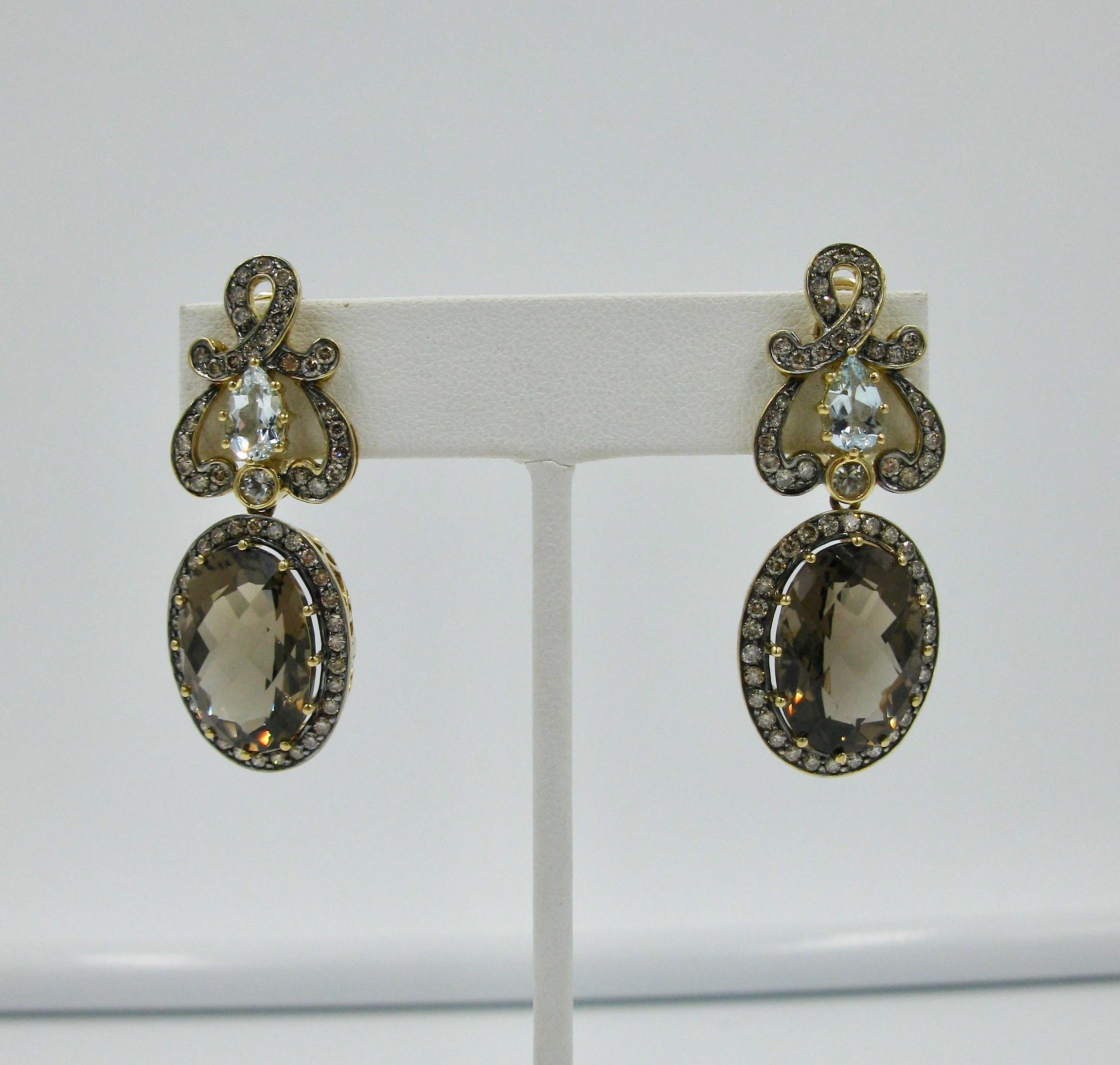 This is a stunning pair of two inch jeweled pendant earrings from the estate of legendary Hollywood writer Jackie Collins.  The earrings with fancy oval cut Smoky Quartz of 3/4 inches in length, with pear shaped Blue Topaz surmounts, and a gorgeous