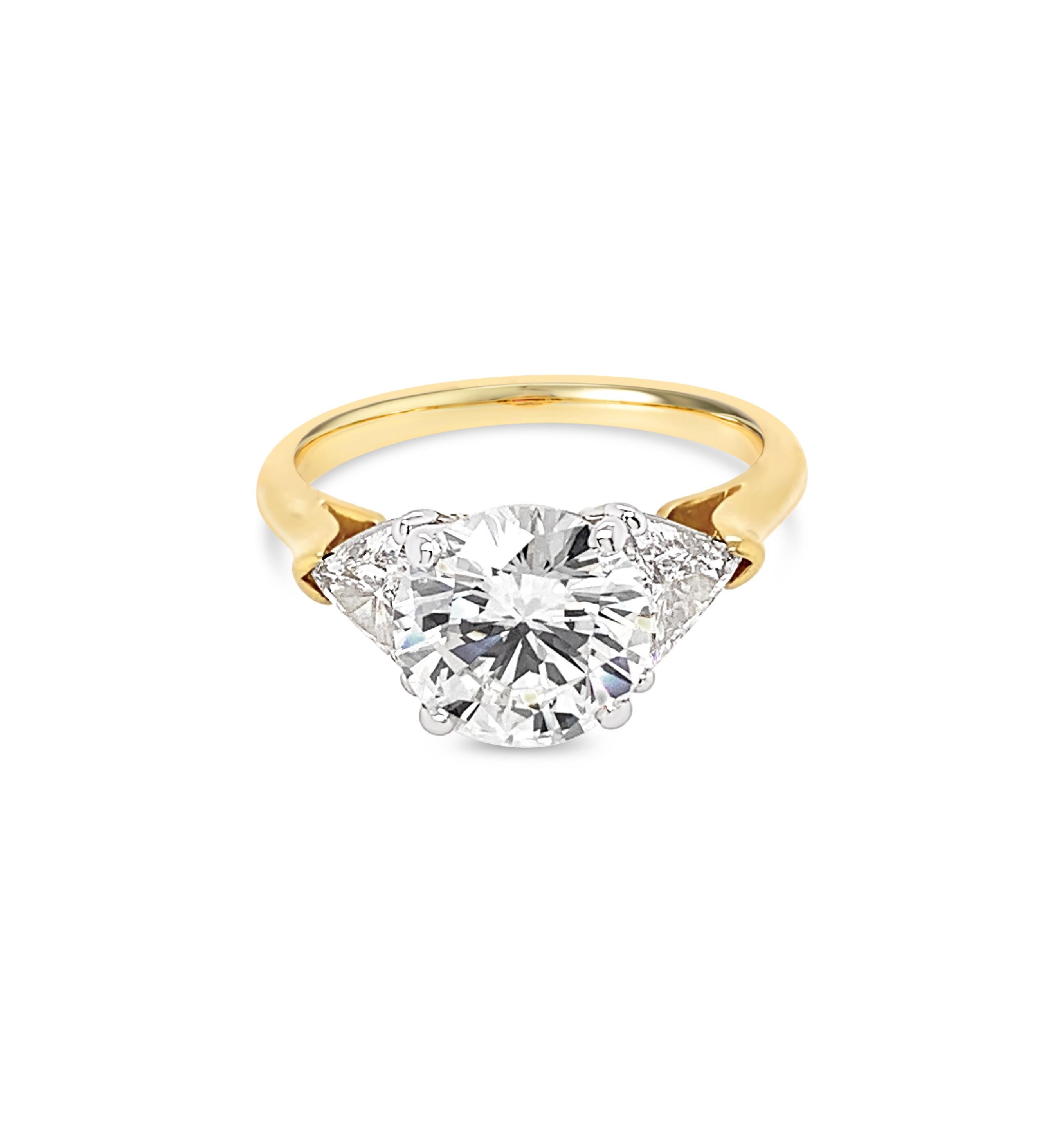 Beautiful 2.25 Carat Round Brilliant Cut Diamond Ring in 18K Yellow Gold with Platinum setting.  Center diamond color grade is G and clarity is VVS-2.  Side diamond trillions weigh 1.00 Carat (total weight).


