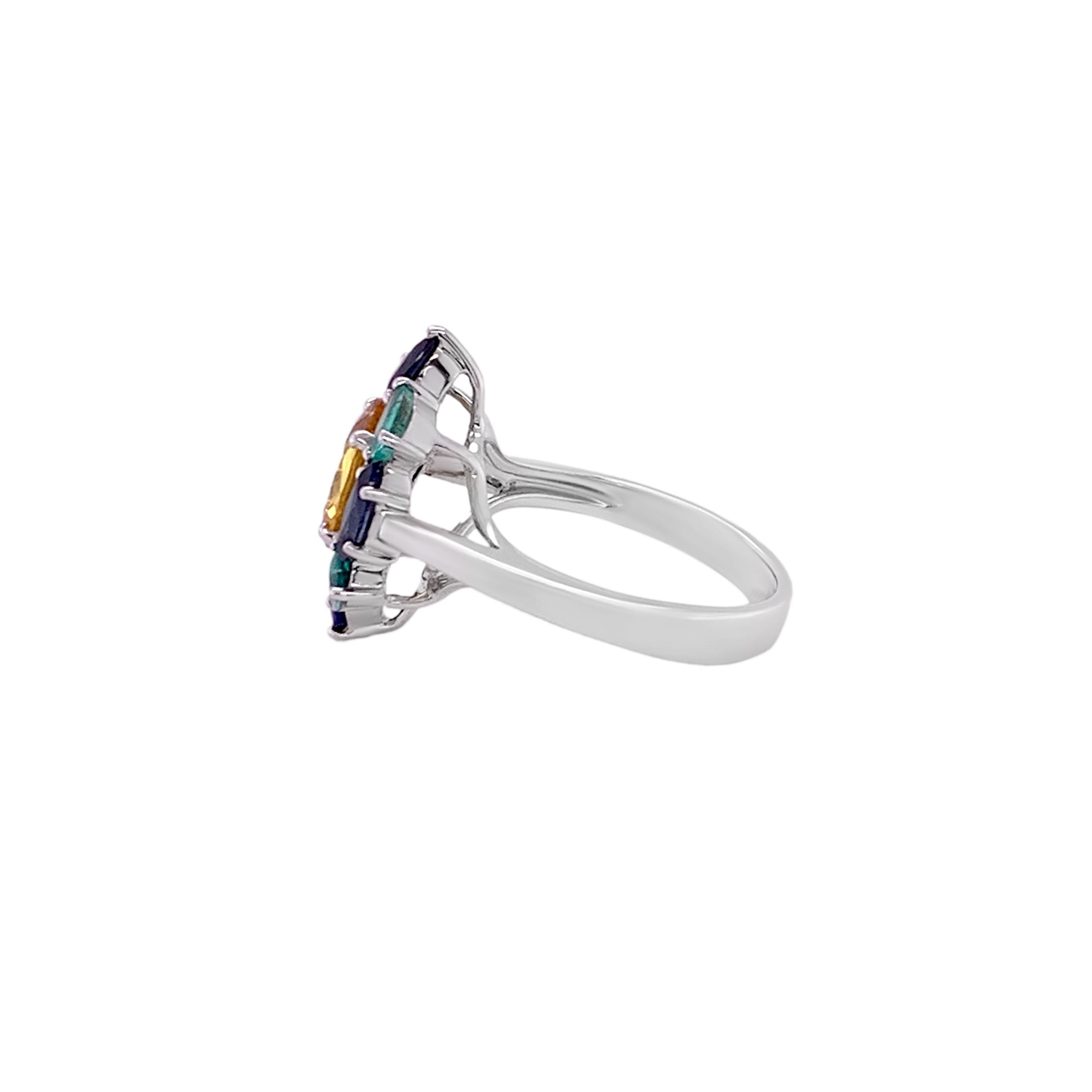 A Tri-Colored cluster ring set in 18 karat white gold with a 2.25 carat Yellow Sapphire center stone surrounded by 0.72 carat pear shaped Emeralds along with 1.23 carat pear and marquise shaped Blue Sapphires.  This ring's design is a delightful