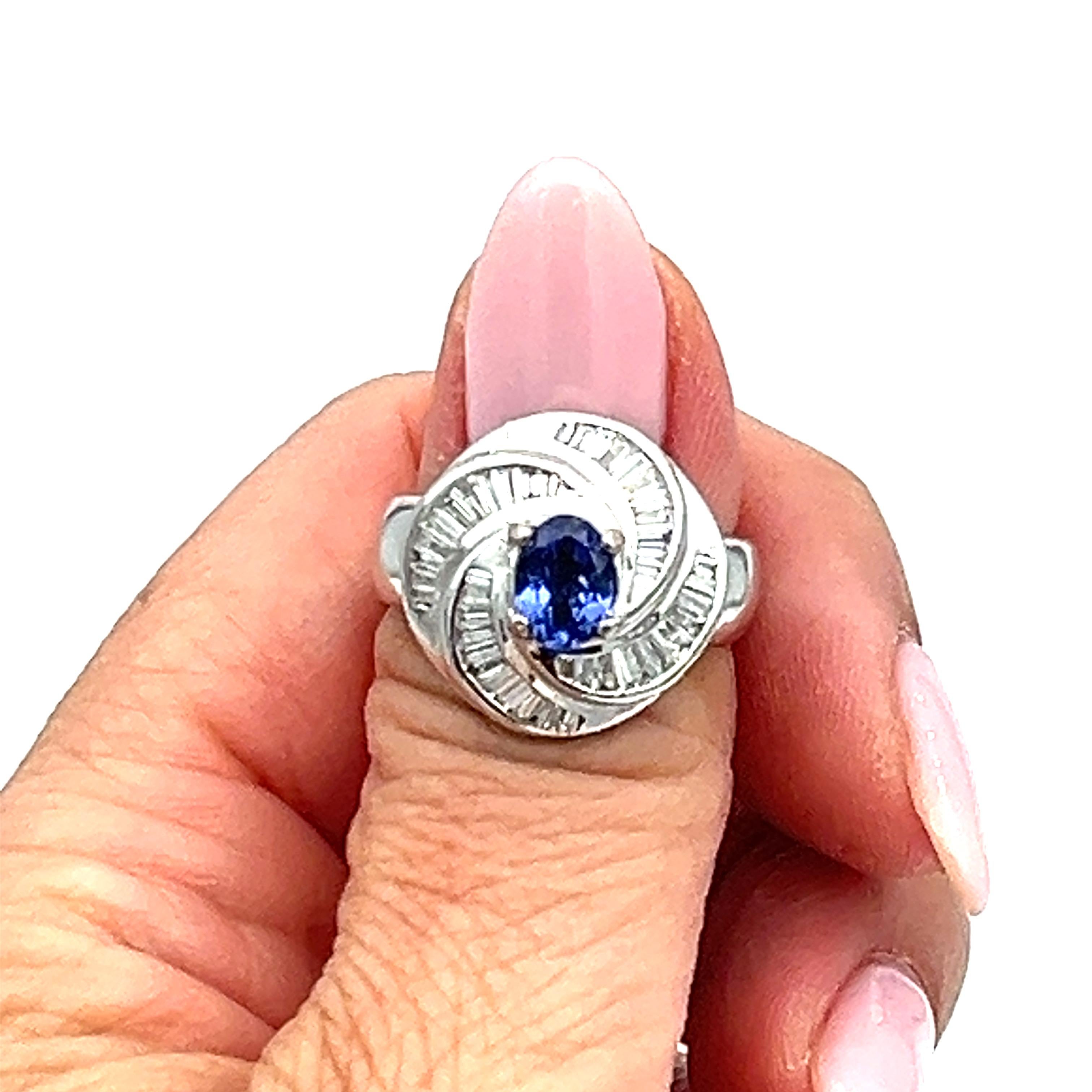 This stunning ring features a gorgeous oval-shaped tanzanite stone in a rich blue color, weighing 1.56 carats, accompanied by sparkling diamonds in a white gold setting. The ring is made of 18k gold, and has a vintage-inspired cocktail style.
