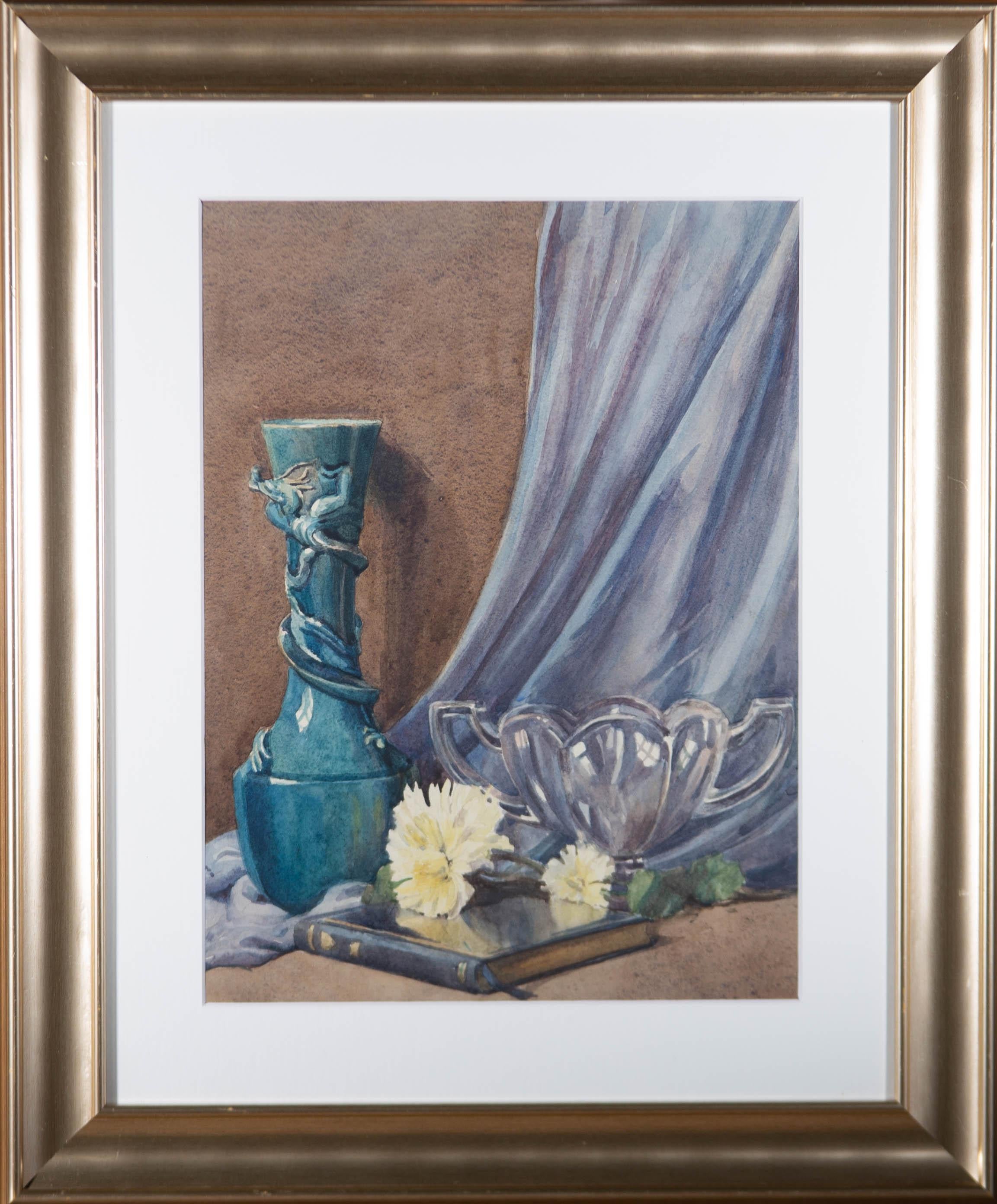 A delightful still life study depicting a blue vase set against a material backdrop, with glassware and spring flowers resting on a book. Well presented in a contemporary frame and white card mount. The signature and date have been cropped and fixed