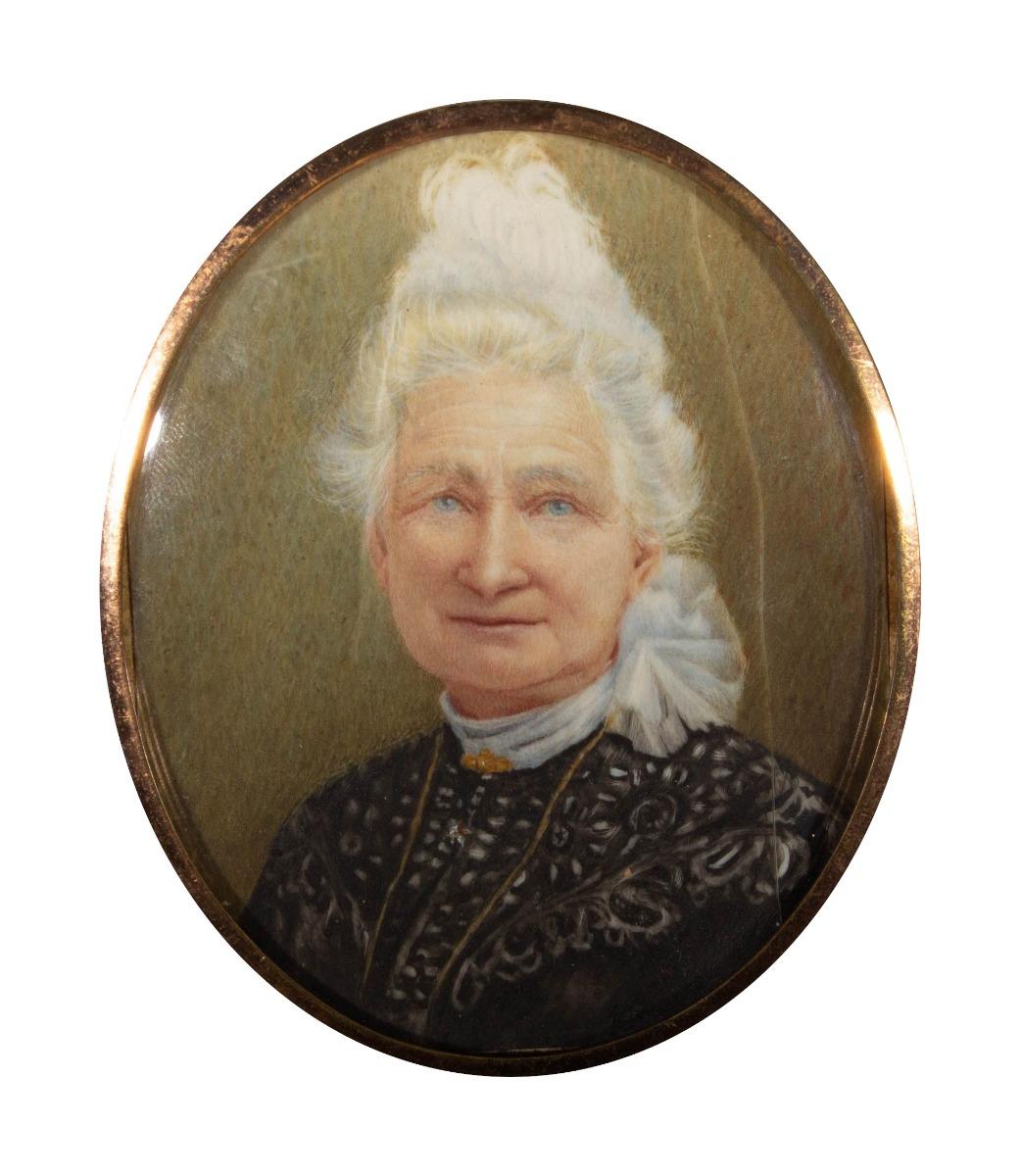 A truly exquisite miniature Victorian portrait of a gently smiling, older woman with fine, lace clothes and elegantly styled hair. The woman has strikingly piercing blue eyes and a warm, subtle smile. unlike many other portraits of older women of