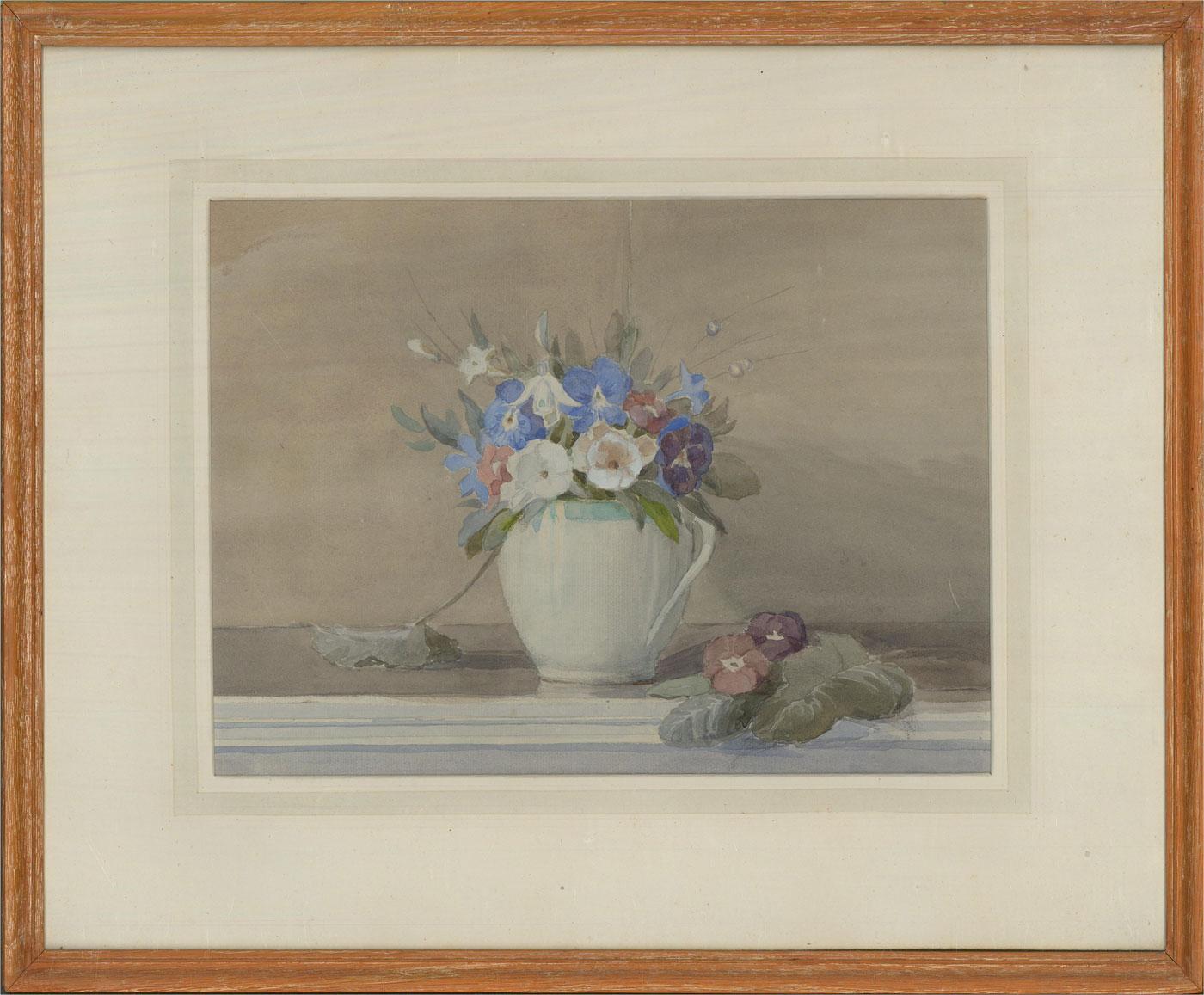 A charming watercolour study of fresh spring flowers presented in a cream jug with blue rim. The jug has been carefully placed on a table top with the excess leaves and flowers left around it. Well presented in a cream mount and simple wooden frame.