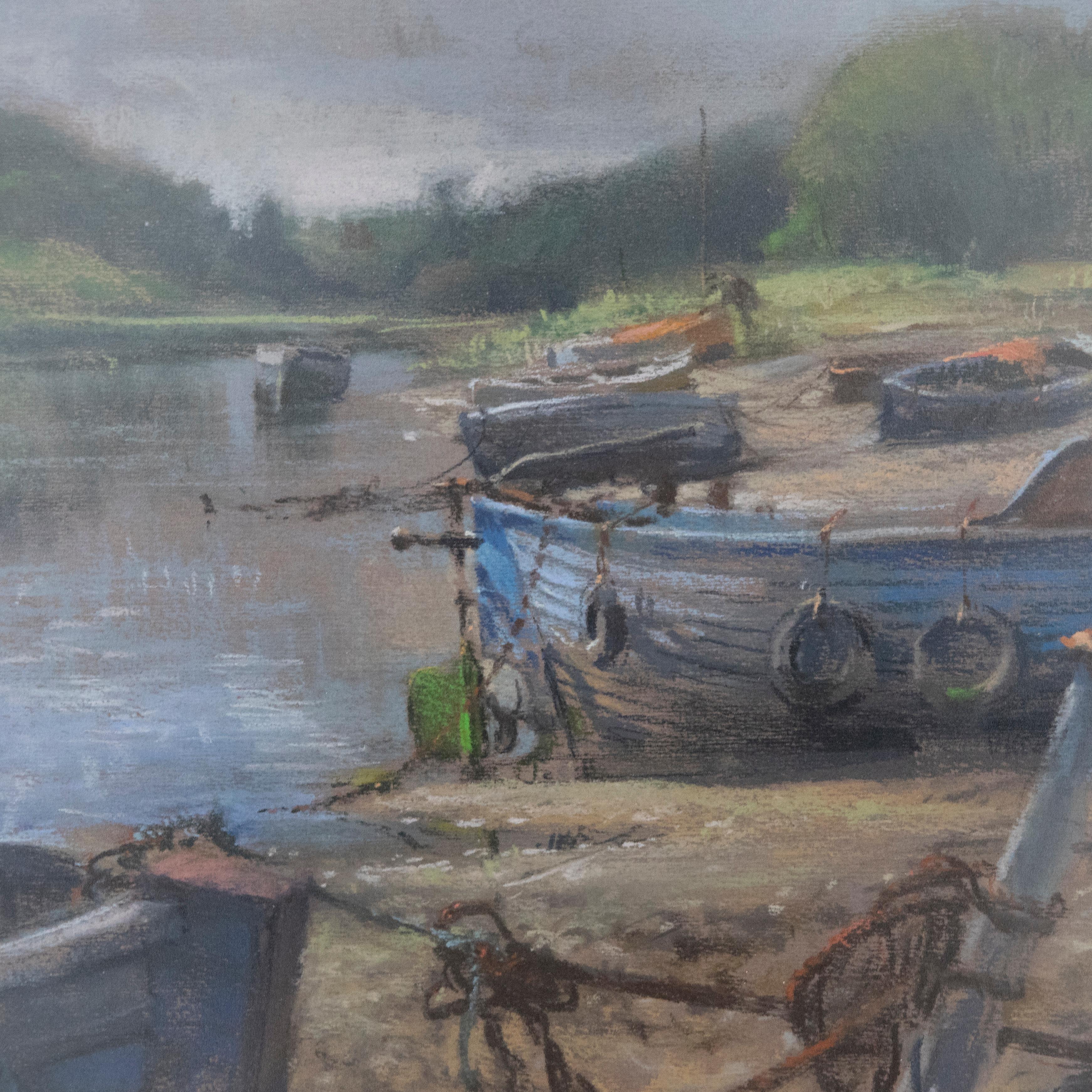 A view of beached fishing boats in an estuary at low tide. Presented in a fine wood frame under glazing. Signed to the lower-left edge. On paper.
