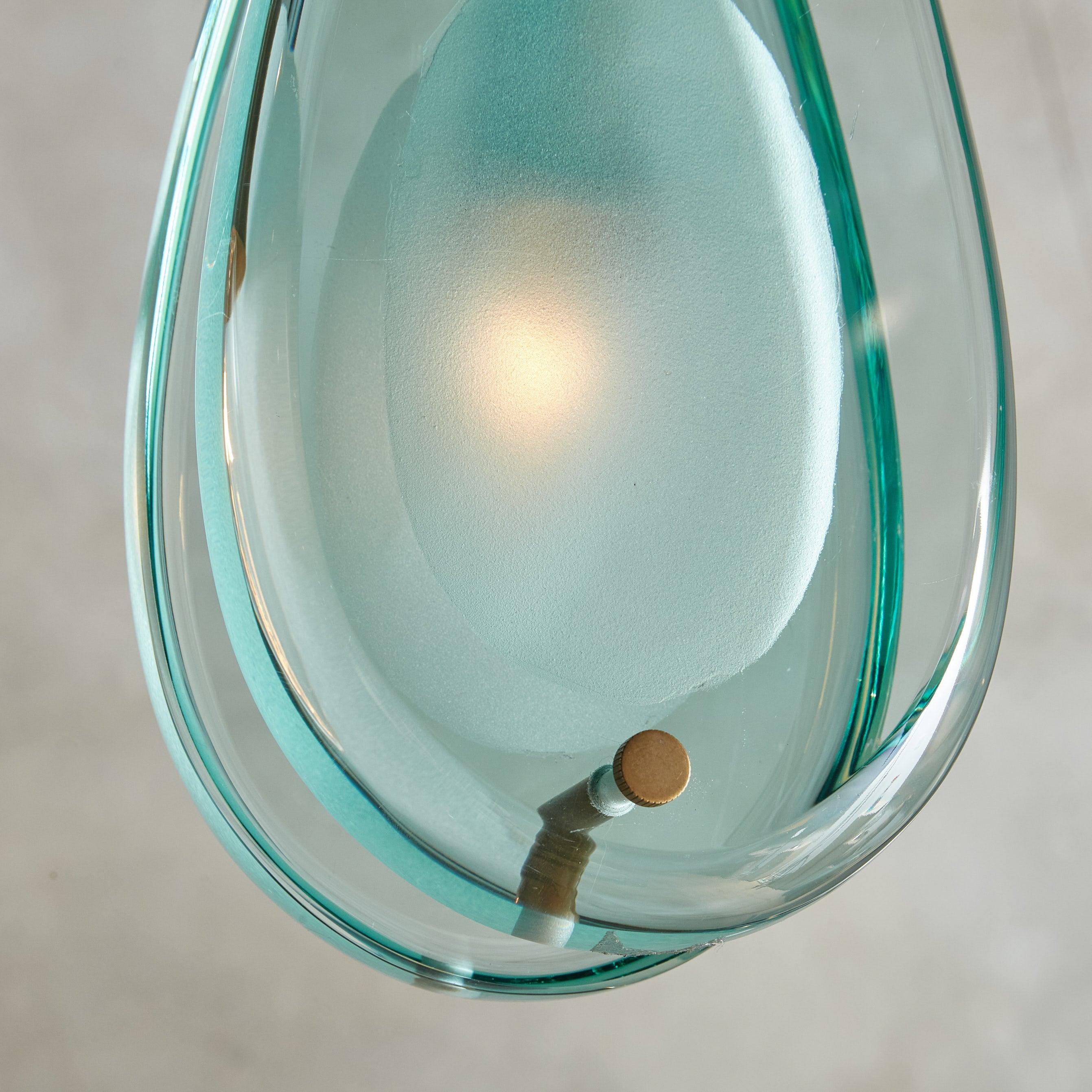 The ‘2259' pendant light was designed by Max Ingrand for Fontana Arte in the 1960s. This modernist design features two teardrop-form glass diffusers with frosted egg-shaped cutouts, subtly obscuring the light source. Suspended from a patinated brass