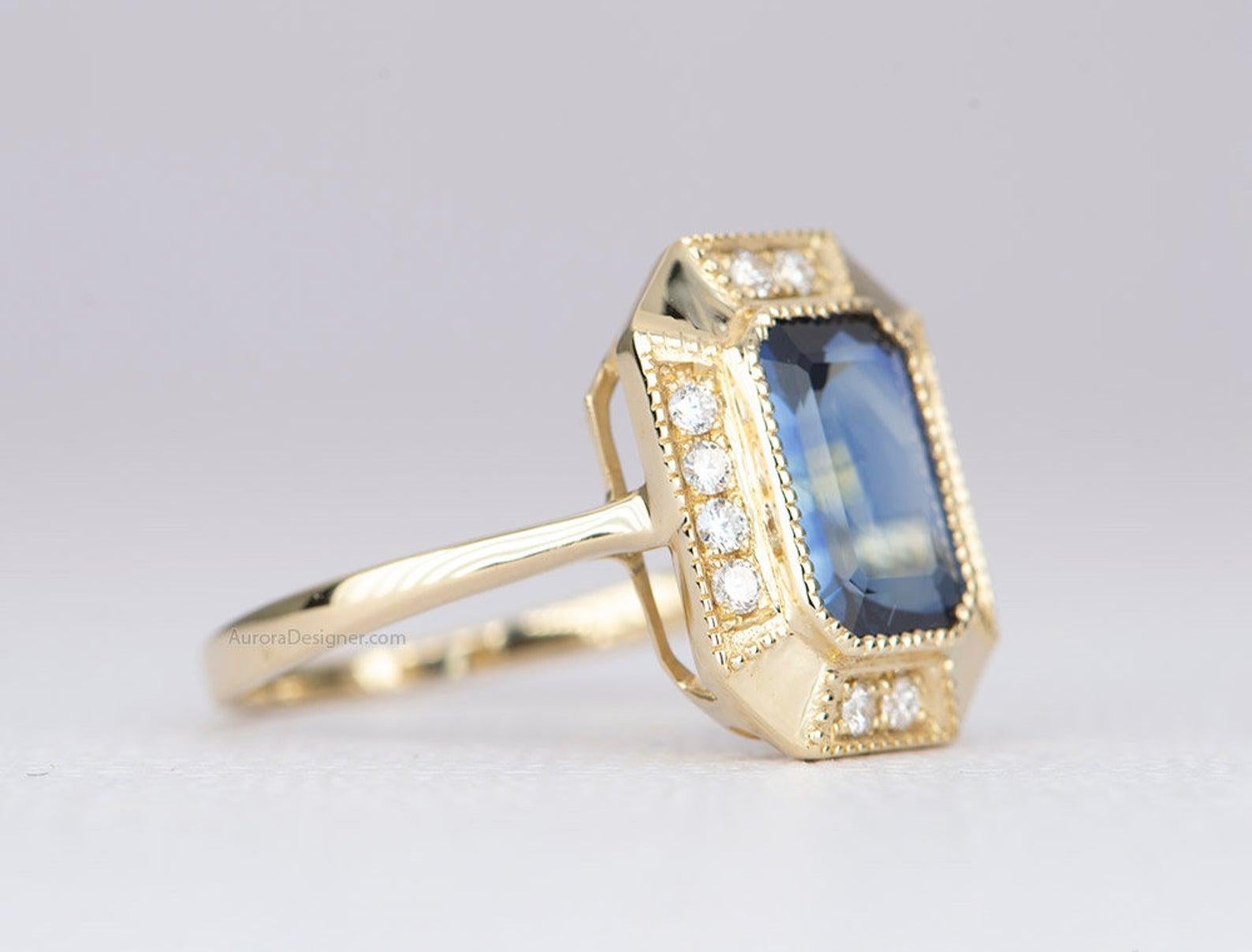 ♥  The center stone is a beautiful 2.25ct emerald-cut sapphire that exhibits a deep blue color with some yellow/green reflection from within.
♥  We bezel set the stone with milgrain edges for an Art Deco-inspired design, then added white full cut