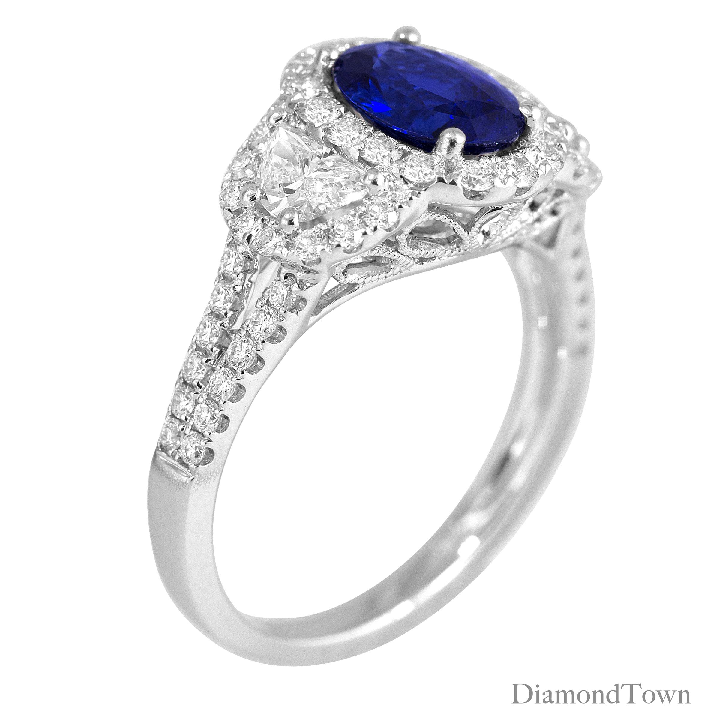 (DiamondTown) This gorgeous ring has an Oval Cut Fine Ceylon Sapphire center measuring 2.26 carats, flanked by two half-moon diamonds and surrounded by a halo of round white diamonds. A double row of round diamonds extend down the split