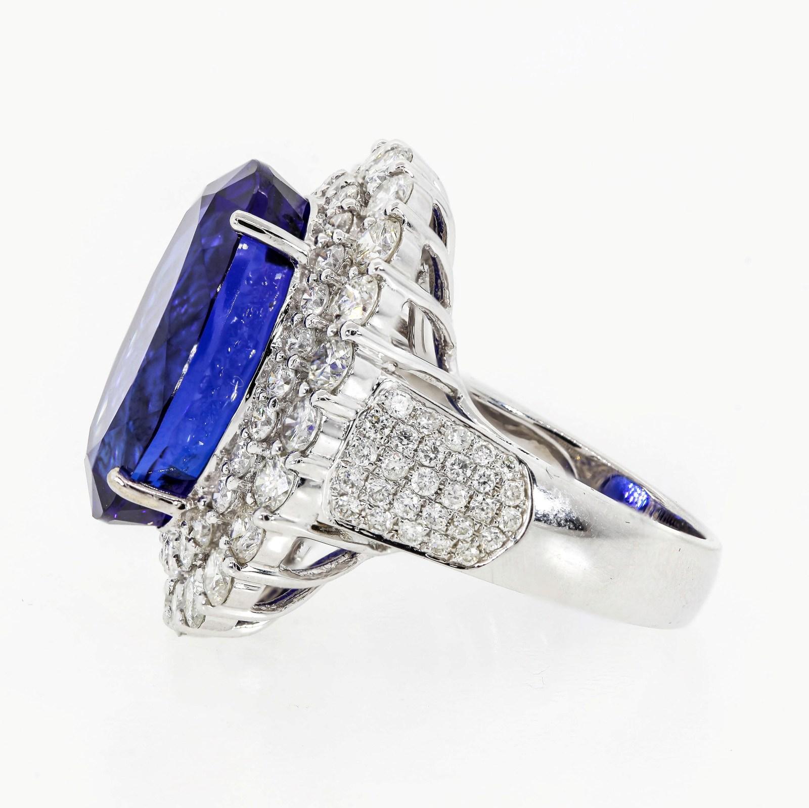 This show stopping bauble features a stunning 22.68 carat oval cut Tanzanite of beautiful deep Royal blue color.  Set in an 18KT white gold, surrounded by concentric rings of sparkly white Round Brilliant Cut Diamonds.  All diamonds weigh 4.30 carat