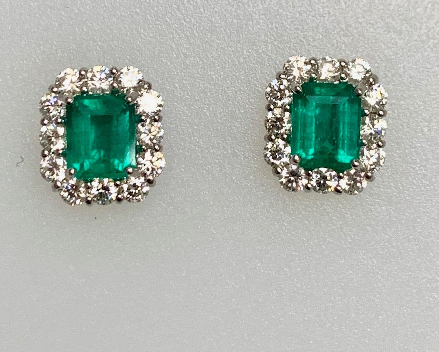 2.27 Carat Emerald cut Columbian emerald set in 18k whit gold earrings with 1.32 ct diamonds around it in classic earrings 