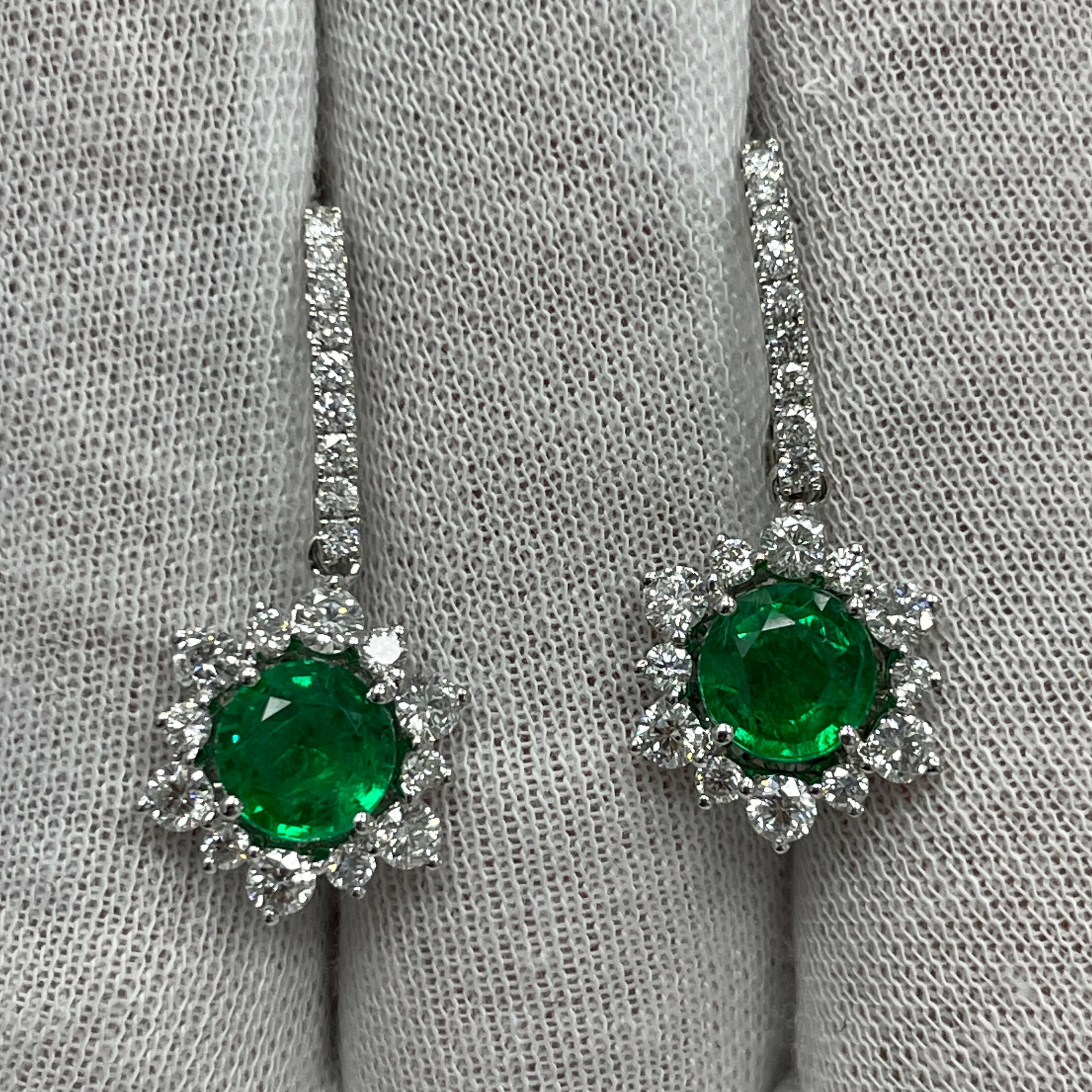 These dangling 18K white gold earrings carry 1.50Ct of brilliant white diamonds and 2.27Ct of stunning matching round emeralds