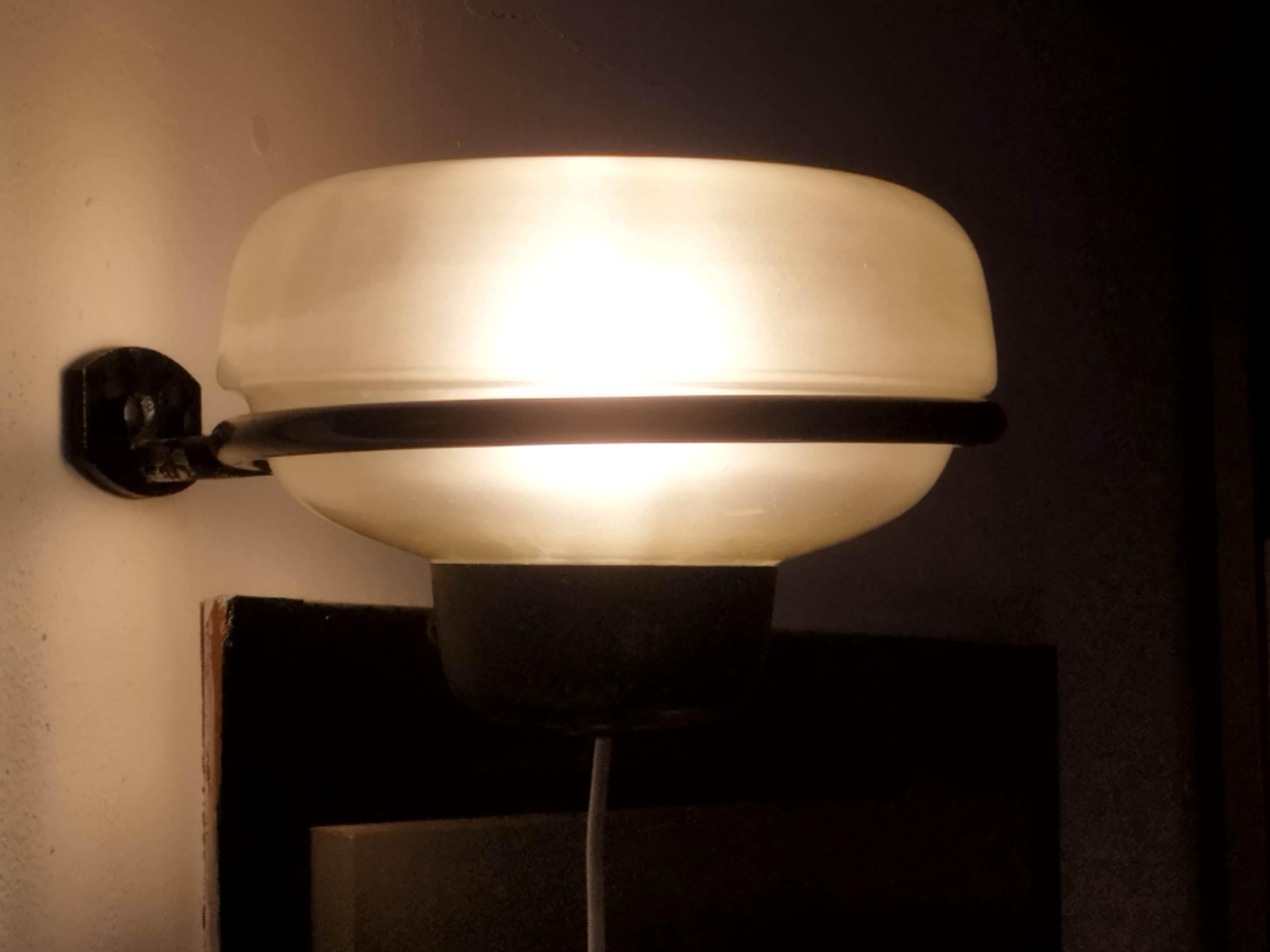 228 wall lamp designed by Gino Sarfatti for Arteluce, one of the most renowned Italian lighting manufacturers. Produced in the 1950s, this stunning piece features a sleek and modernist design, with a slender metal stem and a rounded shade that