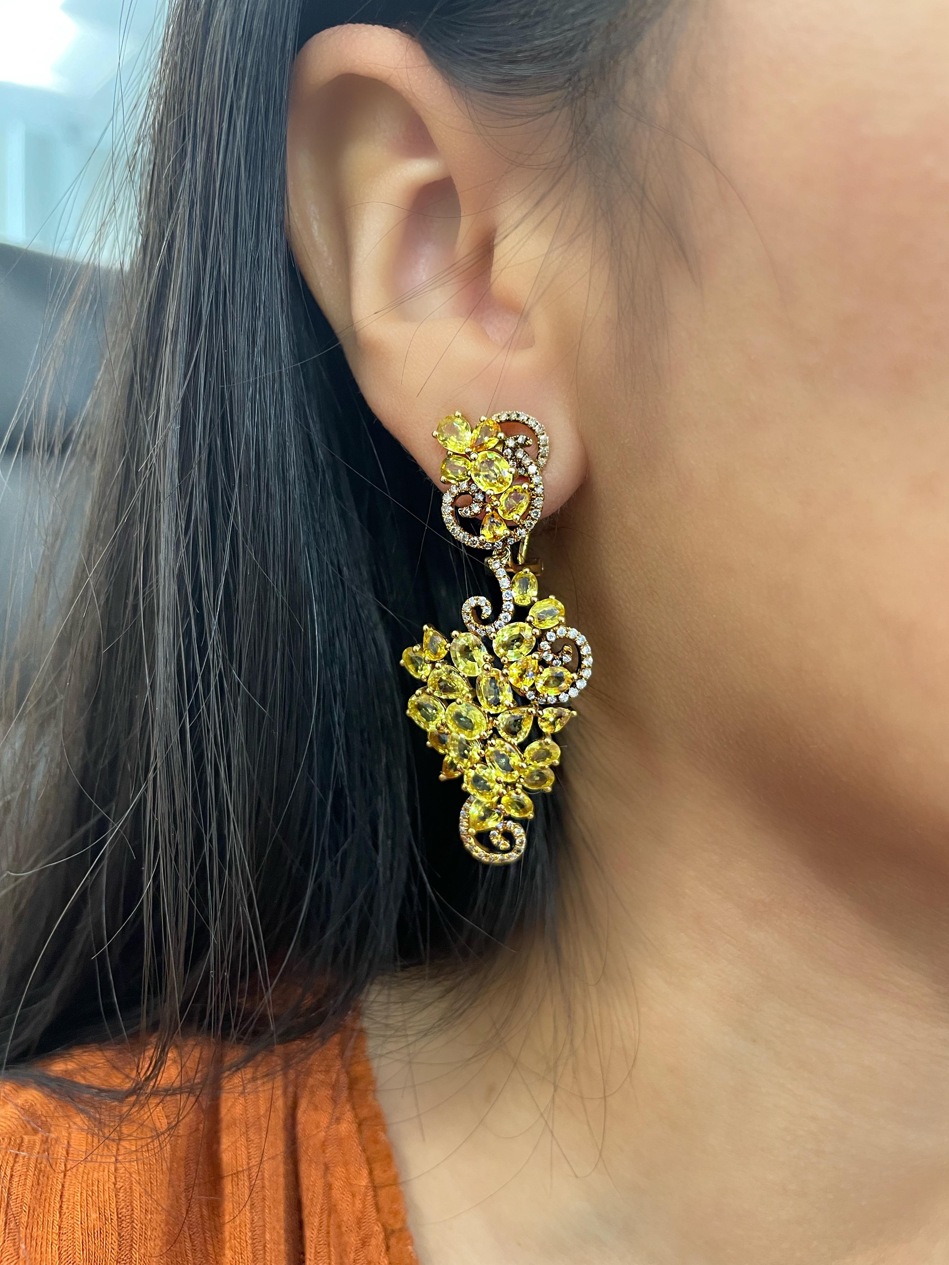  Discover the ultimate elegance and sophistication with these breathtaking 23.98 ctw natural yellow sapphire and diamond earrings. The vibrant yellow sapphires weigh a total of 22.80 carats. They are perfectly complemented by a halo of brilliant