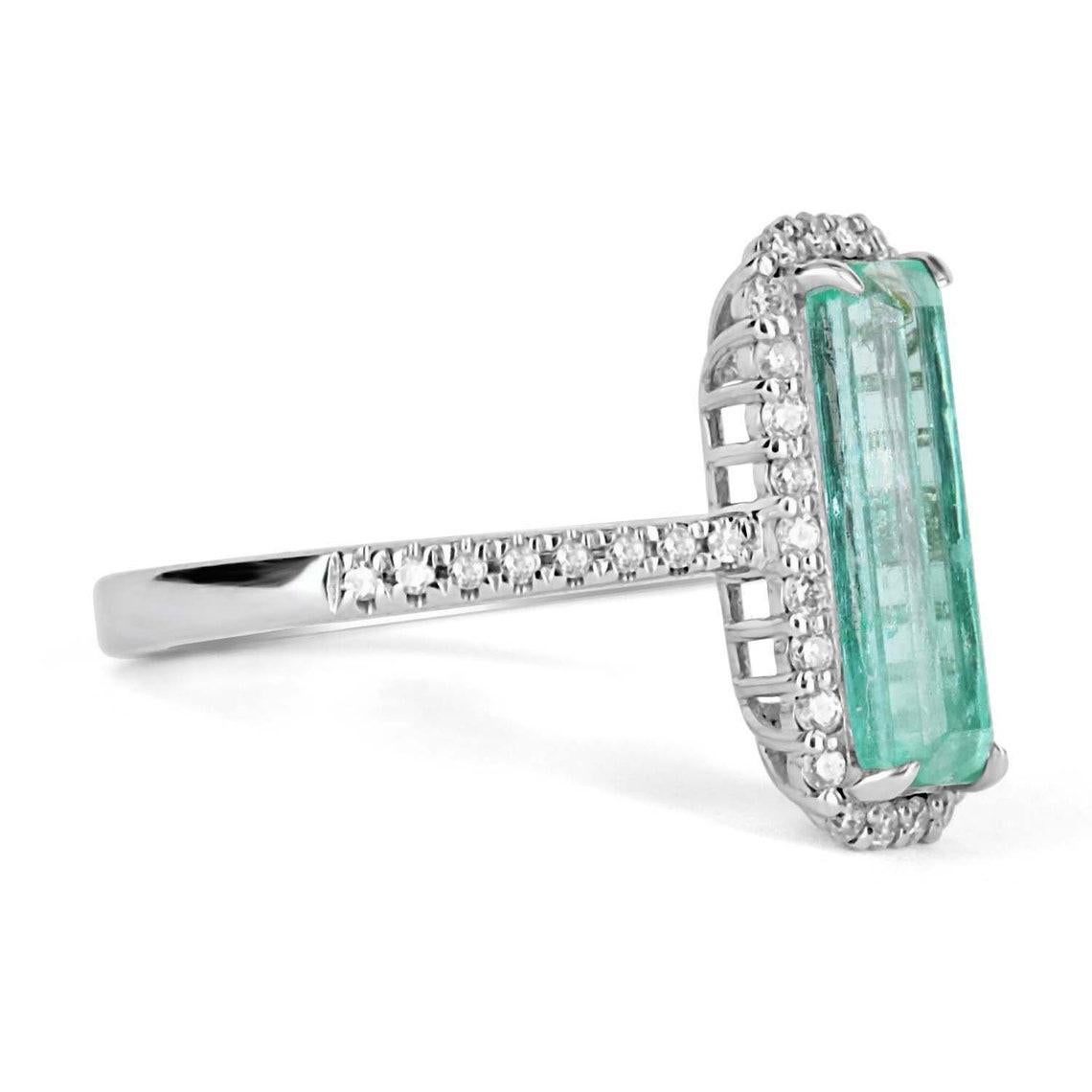 Featured is a bespoke 2.28tcw natural Colombian emerald and diamond halo white gold ring. The center gemstone is a medium-light, bluish-green emerald handset in a 14K white gold prong setting. The emerald has a bluish-green color that is recognized