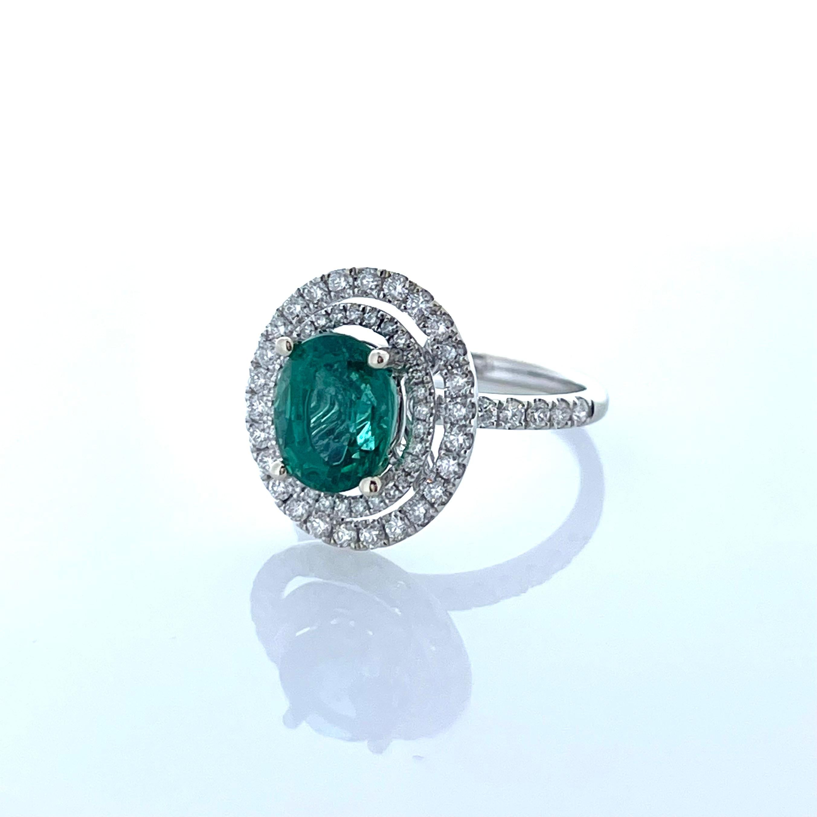 This is a 2.29 Oval cut green emerald. Its transparency and luster are excellent. Sparkling mixed cut diamonds frame this gem in a halo cluster totaling 2.29 carats. Created in brightly polished 18K white gold, this extravagant emerald ring is the