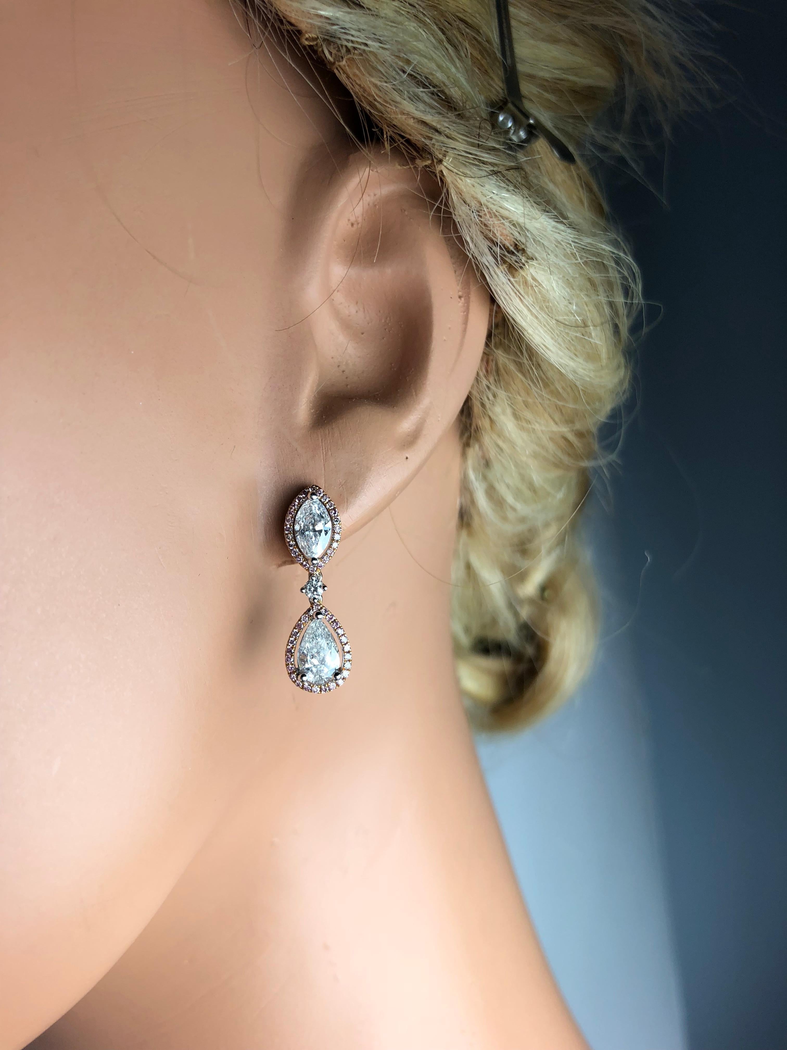 (DiamondTown) These gorgeous stud drop dangle earrings each feature a marquise cut and a pear shape diamond, linked by a smaller round diamond. The center stones are encircled by halos of round pink diamonds.

Two Pear shape diamonds are 1.01