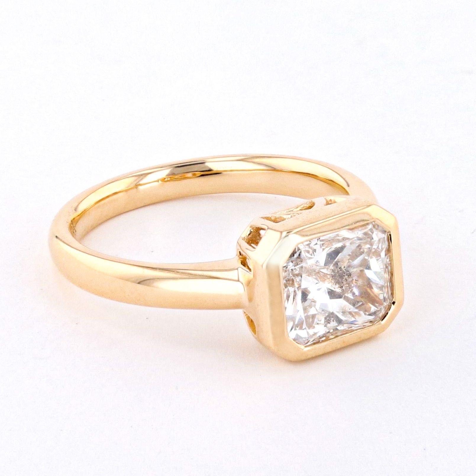 Introducing a breathtaking 2.29 carat radiant cut diamond, beautifully bezel set horizontally in an 18k yellow gold setting. This stunning ring is the perfect choice for those who love bold, contemporary design and want to make a statement with