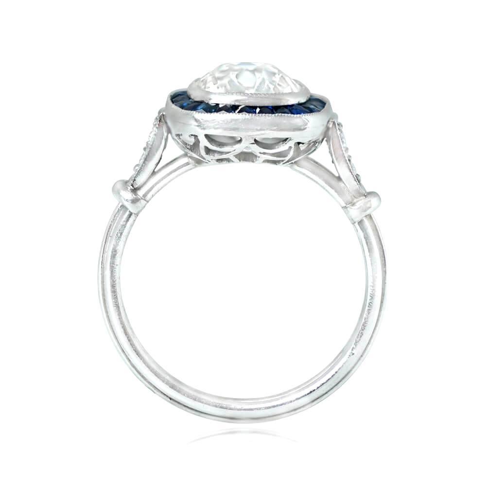 This halo ring features a 2.29-carat antique cushion cut diamond, bezel-set and surrounded by calibrated French cut sapphires. The center diamond has K color and VS1 clarity, while the shoulders have pave-set old European cut diamonds. The ring is