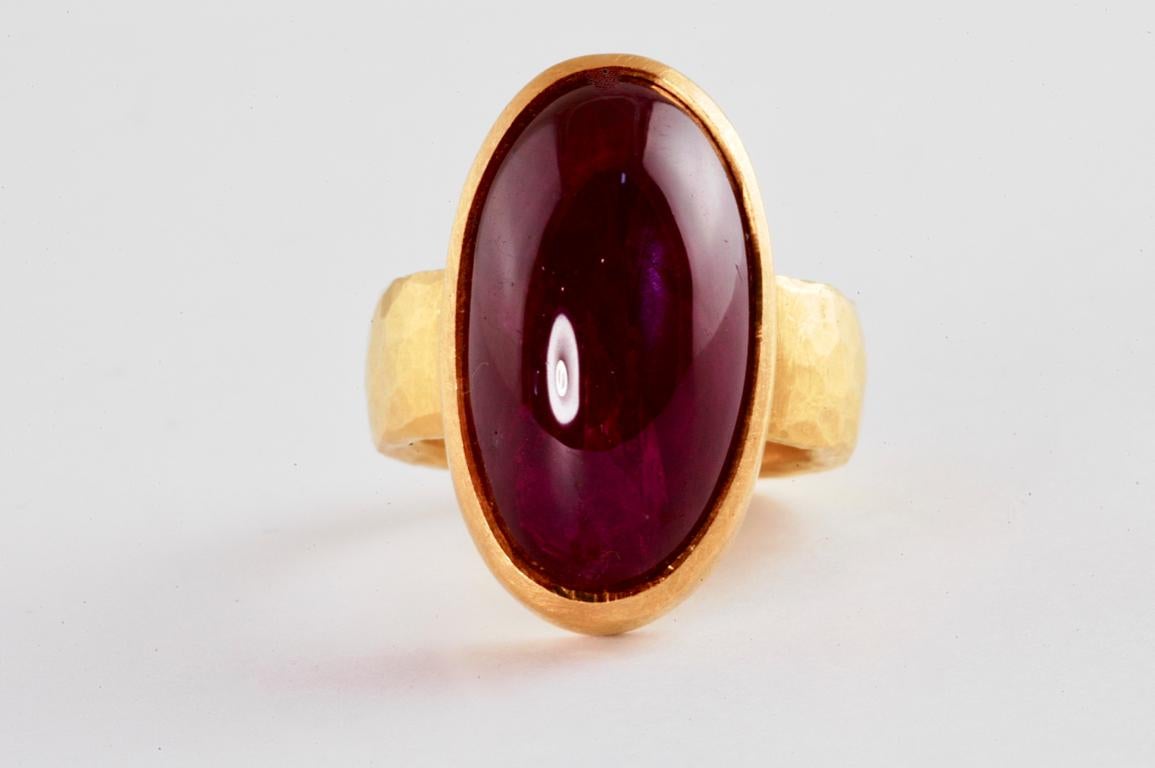 22ct gold ring with large oval cabouchon ruby 27.50cts handmade in Notting Hill, London, by renowned British jeweller Malcolm Betts. This large blood red cabouchon ruby is set on a wide and heavy 7mm 22k gold hammered band. A standout piece, with a