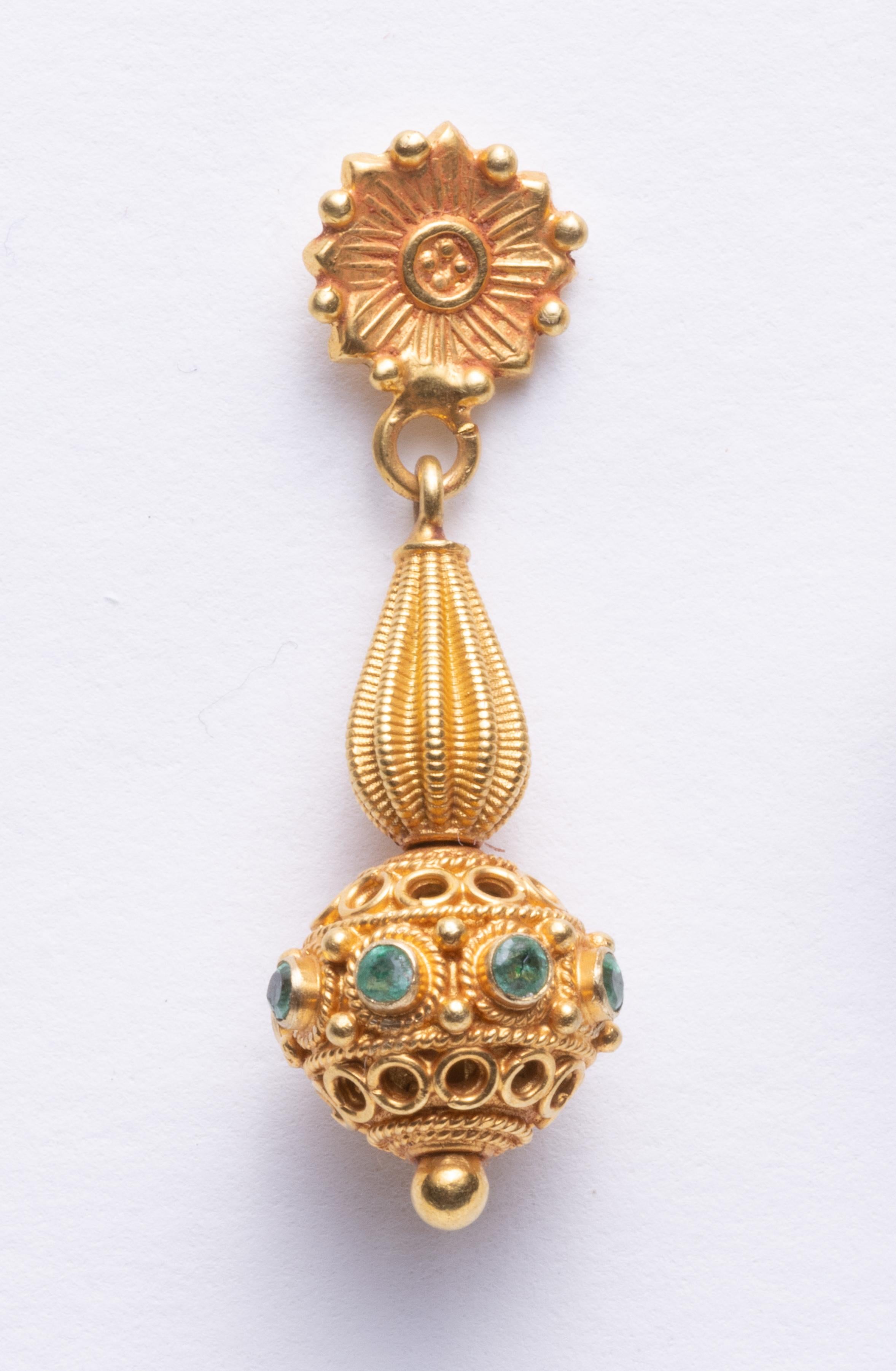 Pair of finely tooled 22K gold dangle earrings with faceted round emeralds around the ball portion.  A floral motif post with detailed workmanship.  Late 1990's.