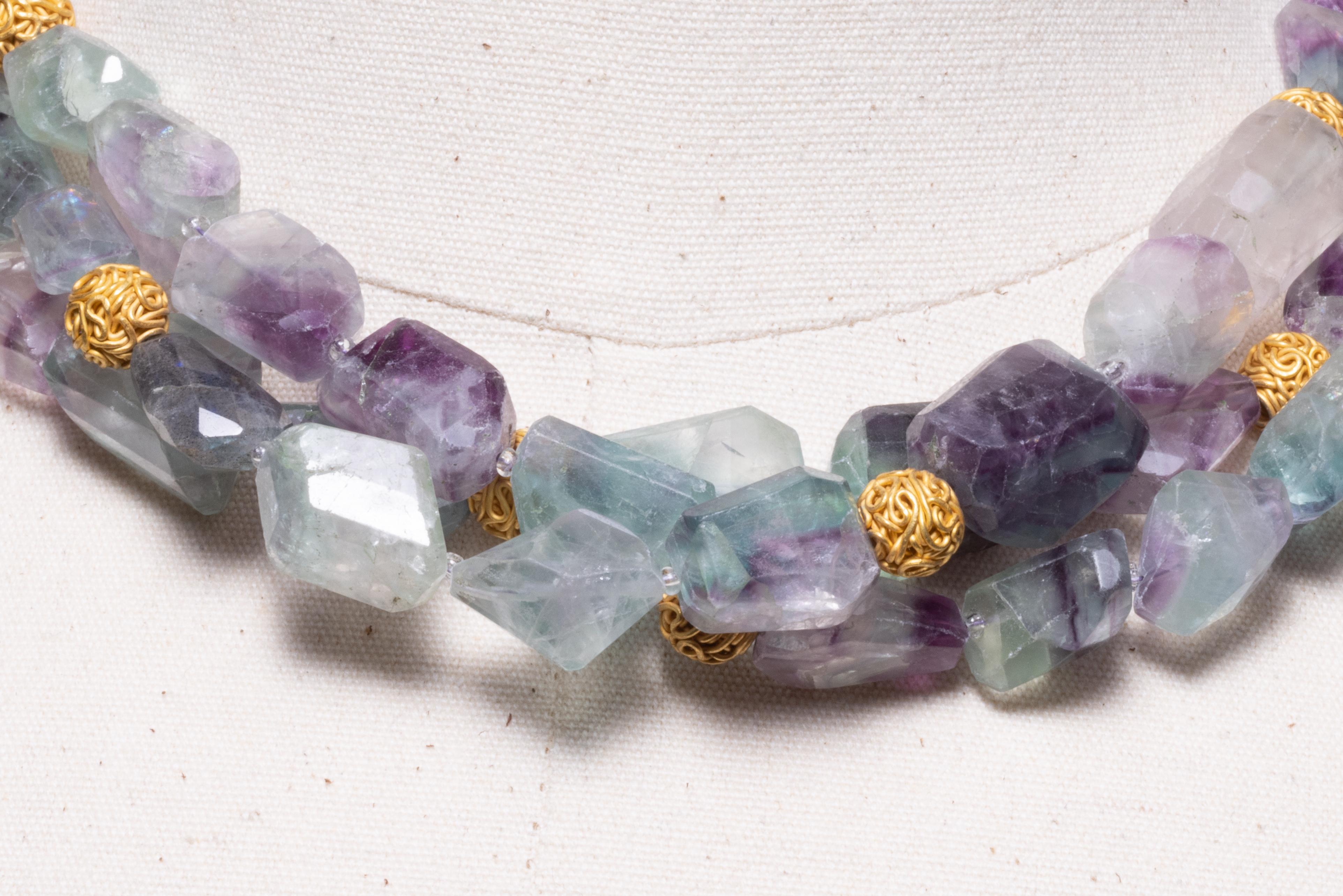 A triple strand necklace of tumbled fluorite beads interspersed with 22K gold beads and chain along the back with a screw clasp.  By Deborah Lockhart Phillips.  Lovely hues of purple, blue and green. 