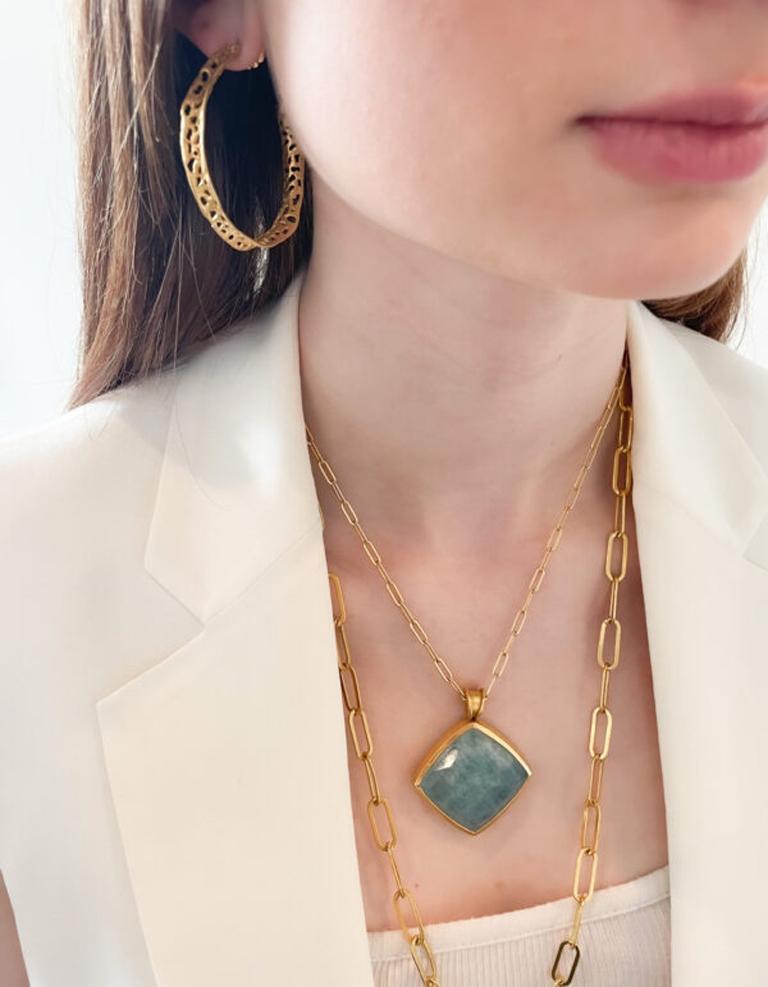This gorgeous Aqua pendant is beautifully set in a traditional 22k gold bezel. Beautiful matte finish and custom bail accents this aqua stone perfectly. Sold on a 16” paperclip chain. Stone 25×25mm

The Tagili Promise: With every piece sold a