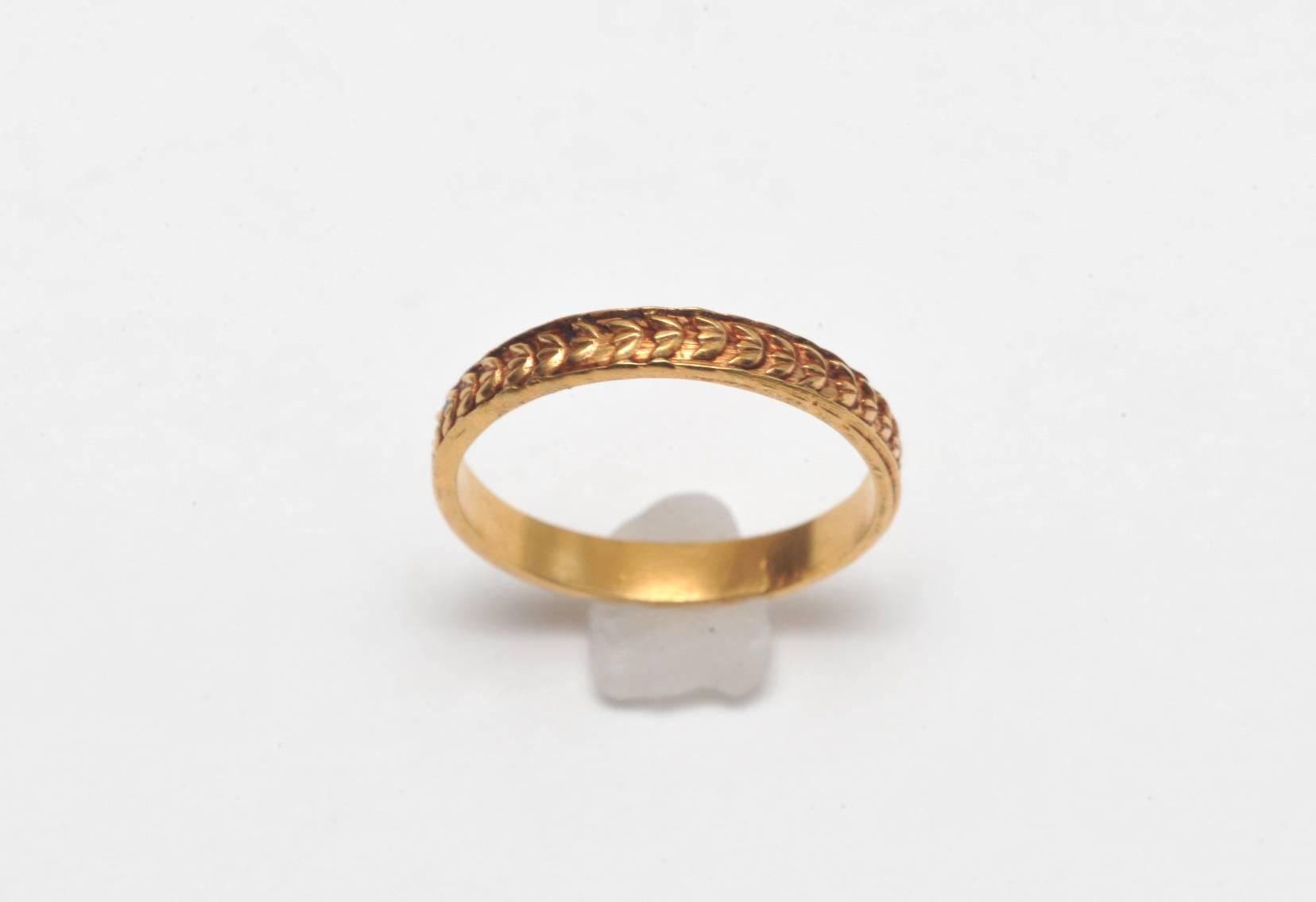 Unusual and different, a 22K gold band with hand-tooled laurel wreath design all the way around.  Size is 7.5.