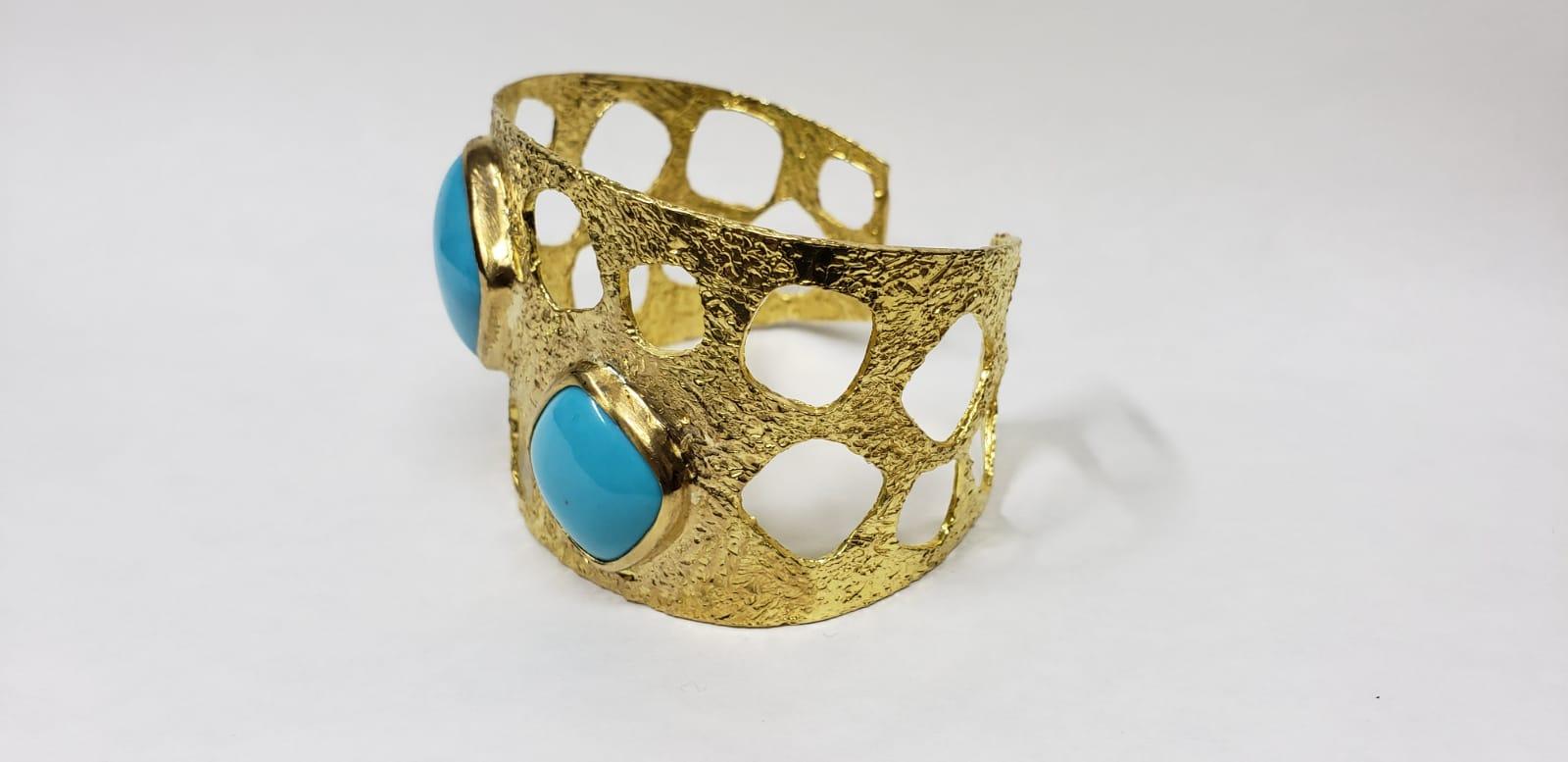 22k gold statement cuff is carefully handmade and hand sculpted featuring 2 beautifully set turquoise cushion cut stones and significant attention to detail With the combination of Tagili’s signature finish and the vibrant color of turquoise blended