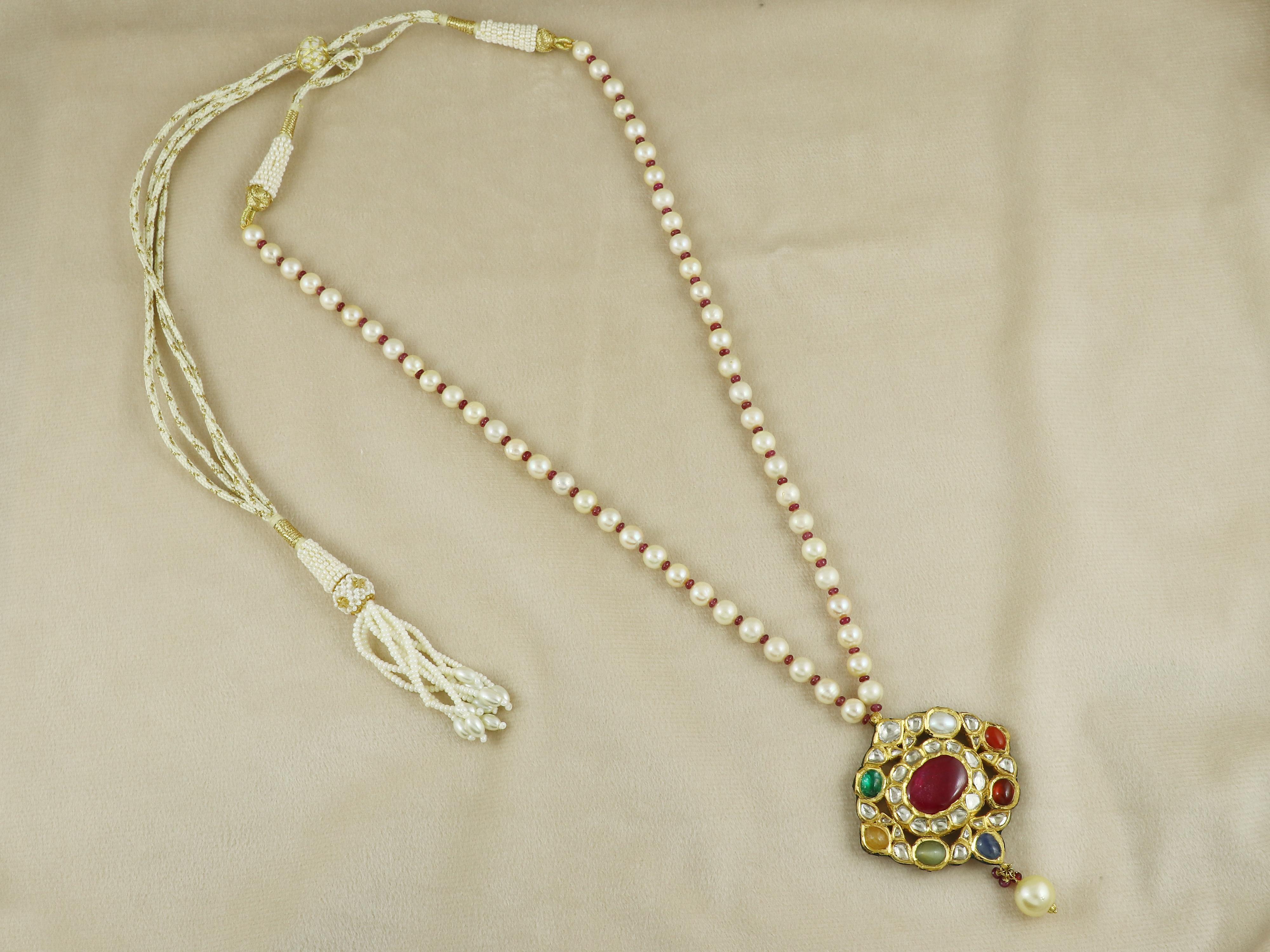 Pendentif Navratna en or 22K serti de neuf pierres précieuses et d'un polki en diamant naturel (tranches de diamant non taillées). Le pendentif est composé d'un rubis de Bangkok, entouré de polkis de diamants taillés en rectangle, de perles de