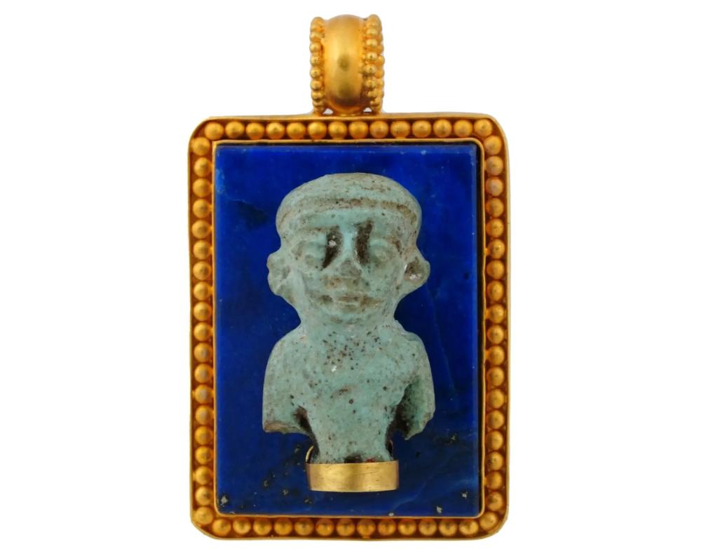A vintage 22K gold amulet pendant adorned with an ancient Egyptian faience god figure. Mounted on a finely carved lapis lazuli piece and encased within a luxurious golden frame, every detail of this pendant speaks of opulence and sophistication.