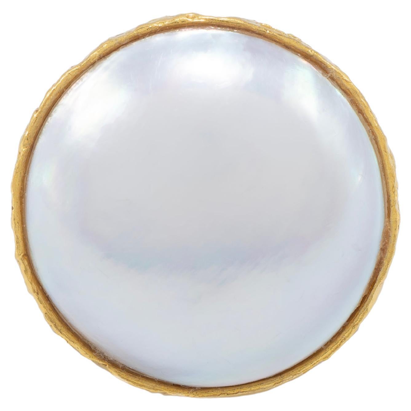 La bague cocktail Mabe Pearl Signature est sertie d'or 22k et dotée d'un double anneau pour un effet encore plus spectaculaire. Complète avec la finition signée Tagili Designs. Chaque saison, une nouvelle pierre est mise en vedette,