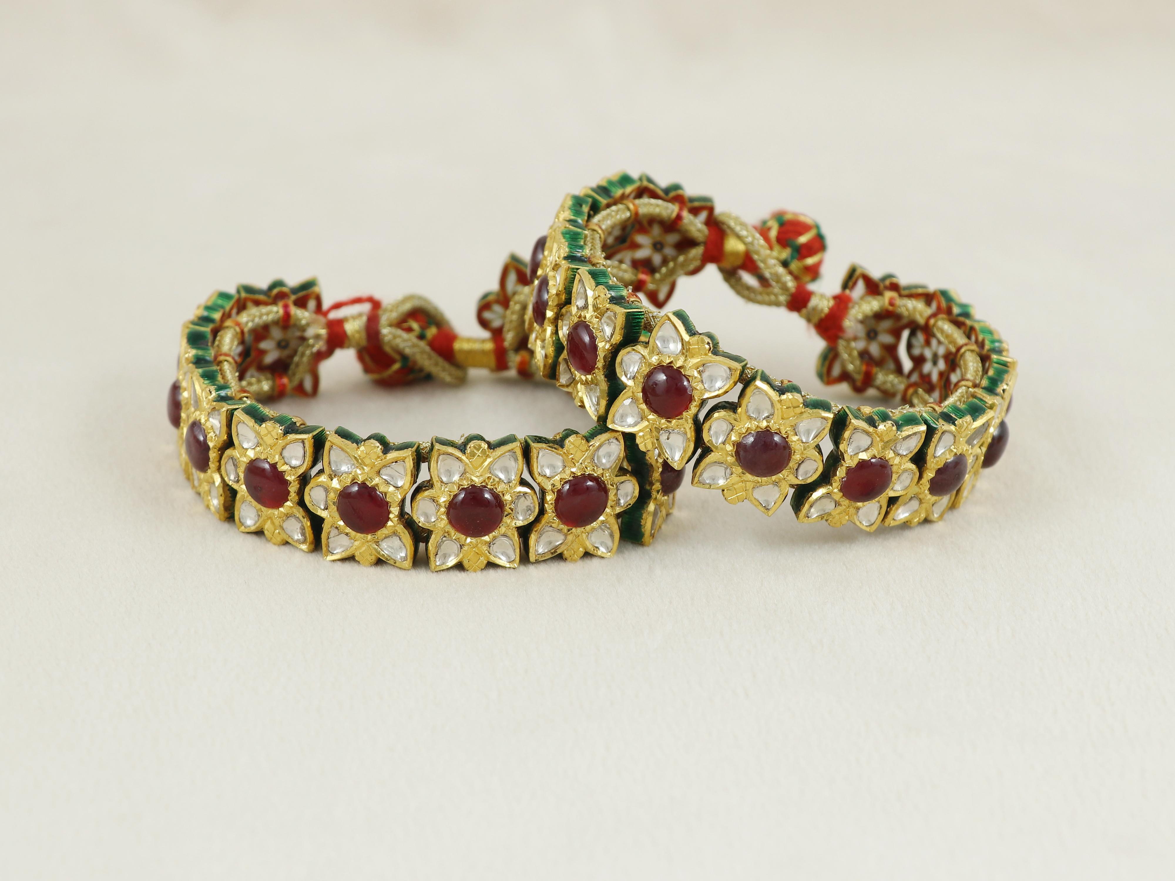 Una coppia di bracciali in oro 22 carati, ciascuno composto da 13 pezzi in pannelli a forma di fiore. Ogni pannello è incastonato al centro con un rubino di vetro circondato da petali di diamanti polki incastonati in kundan. 

I polacchi utilizzati