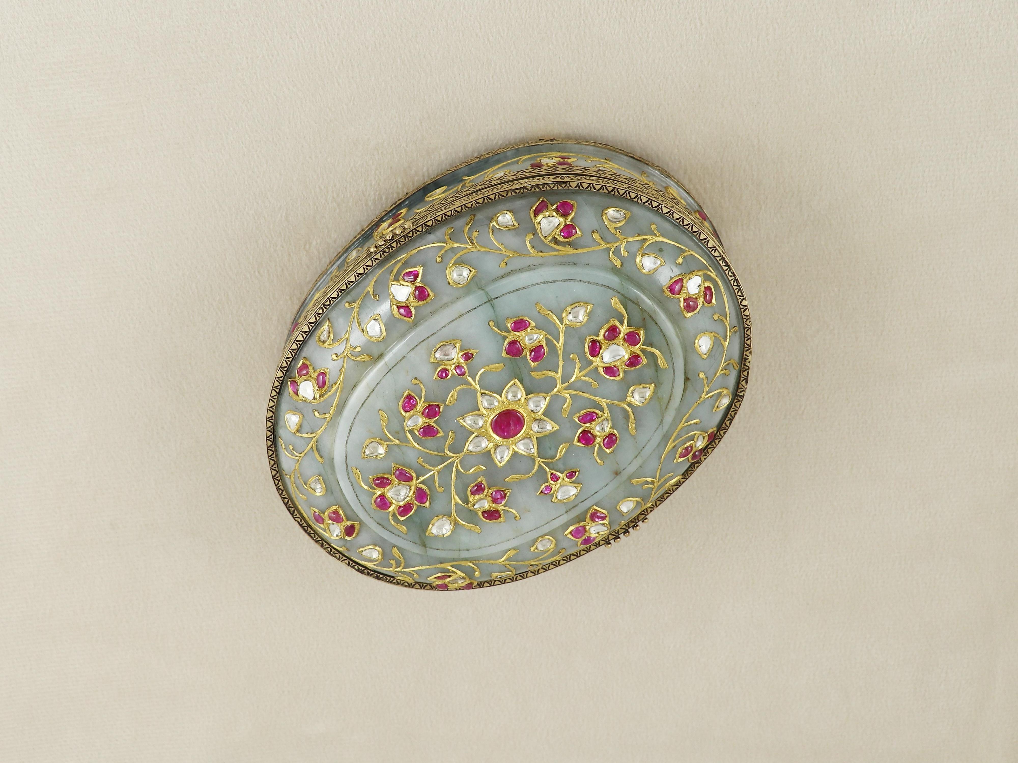 A striking union of regal artistry and masterful gemcraft, this exquisite oval box is meticulously carved from fine jadeite jade and adorned with 22K solid gold detailing. The body of the box, fashioned from a single piece of lustrous green jadeite,