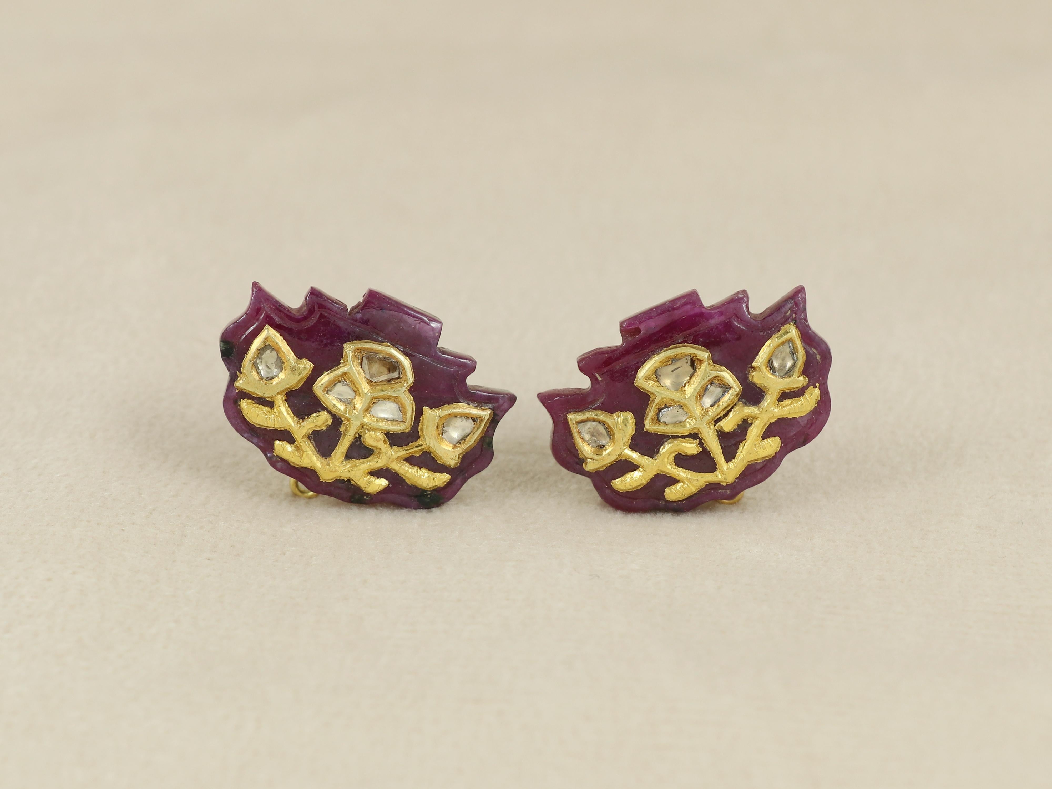 A carved pair of rubies mimicking fan shaped architecture found in old Indian building natively in Jaipur, India.

The carvings are inlaid with 24K gold and diamonds forming a flower motif with gold mechanism at back to help wear the pair. The pair