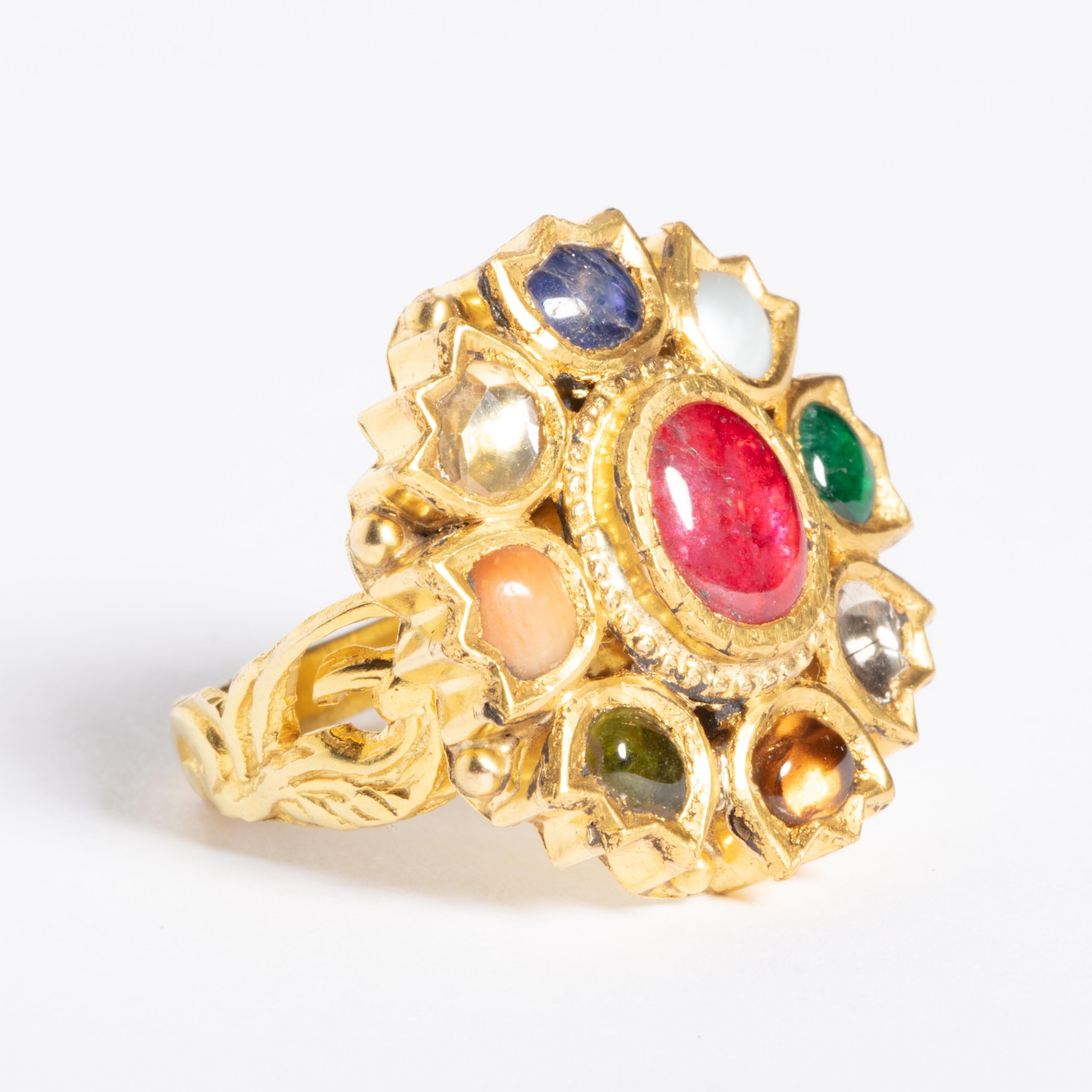 A 22K gold ring depicting the NavaRatna, a combinations of precious and semi-precious stones bringing good fortune to the wearer.  Hand-tooled workmanship with peacocks along the sides of the band.  Ring size is 7.5  Mid 1900's.

The mythology of