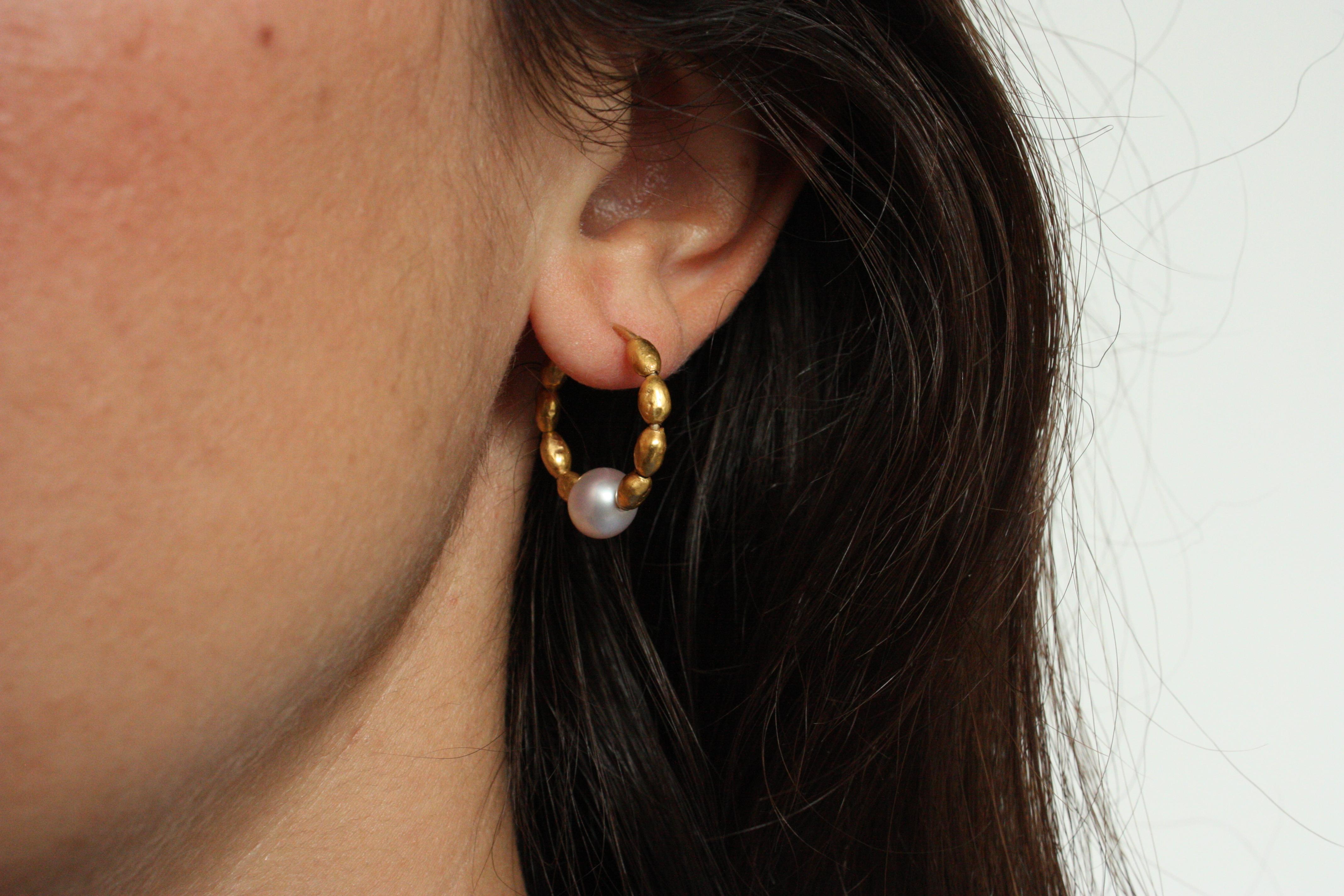 These handcrafted hoop earrings feature a striking combination of 22k yellow gold nuggets and lustrous pink cultured pearls. Each nugget is individually shaped, giving the hoops a natural, organic texture, while the pearls offer a soft contrast with