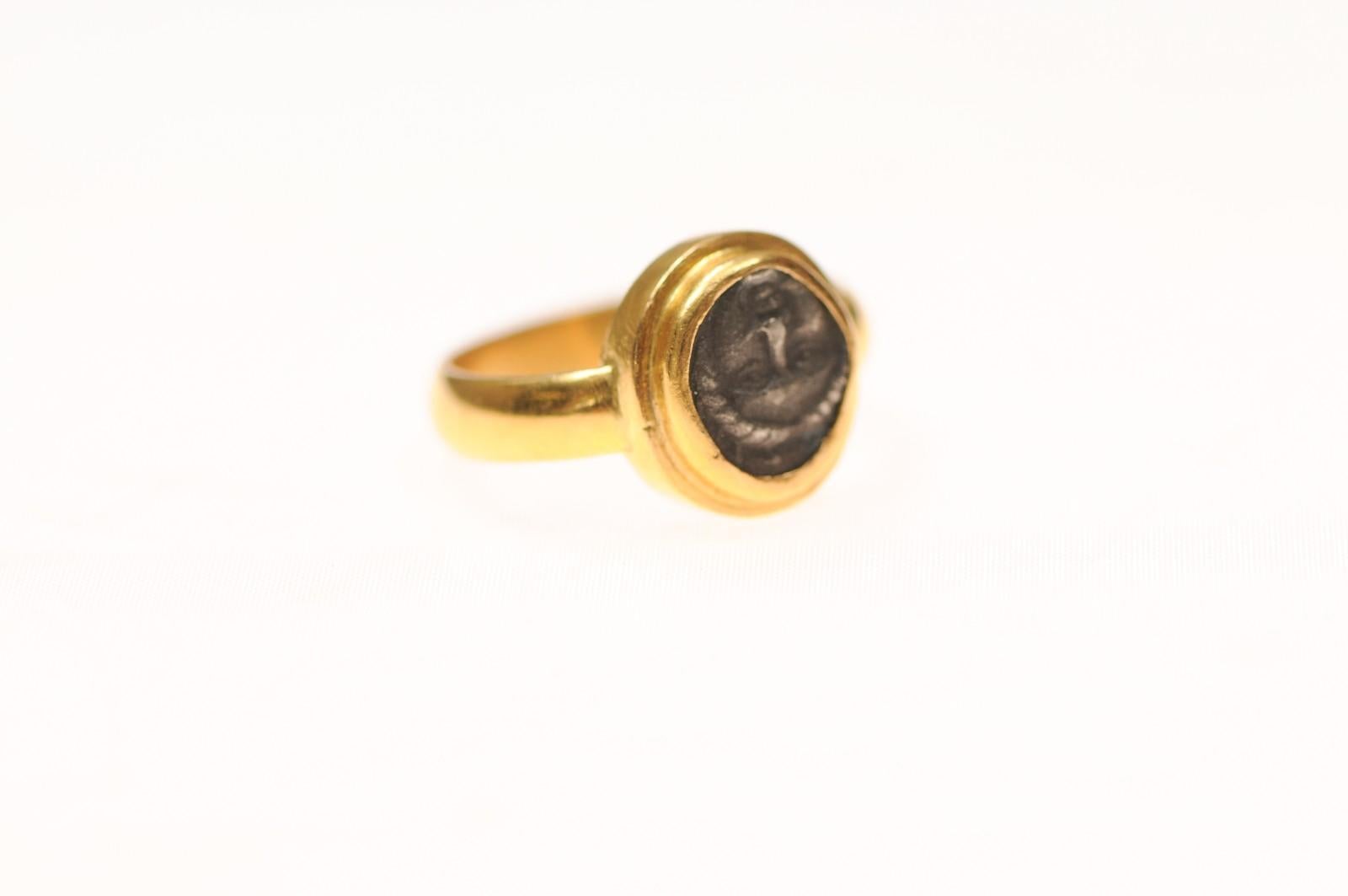 Anillo de oro de 22 quilates con un Dibol [moneda] de plata acuñado en Apolonia Pontika, hacia los siglos V-IV a.C. En el anverso, está el rostro de Apolo, enmarcado con un perímetro redondo plano de oro de 22 quilates. En el reverso hay un ancla