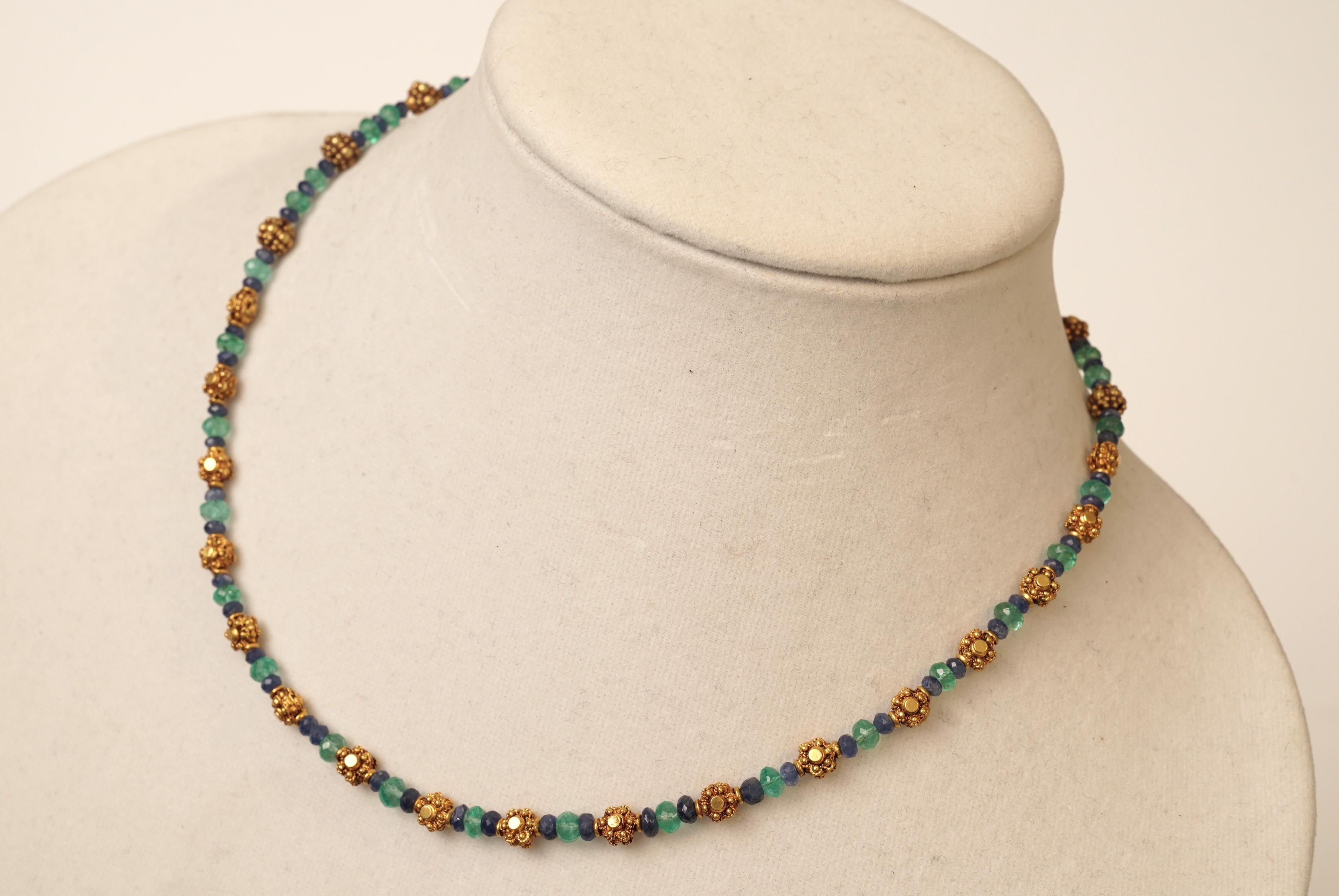 A delicate yet significant 22K gold necklace with faceted blue sapphires and faceted Colombian emeralds.  The gold beads have a flower motif and have significant gold weight and fine granulation work.  S-hook clasp and extra chain to convert between