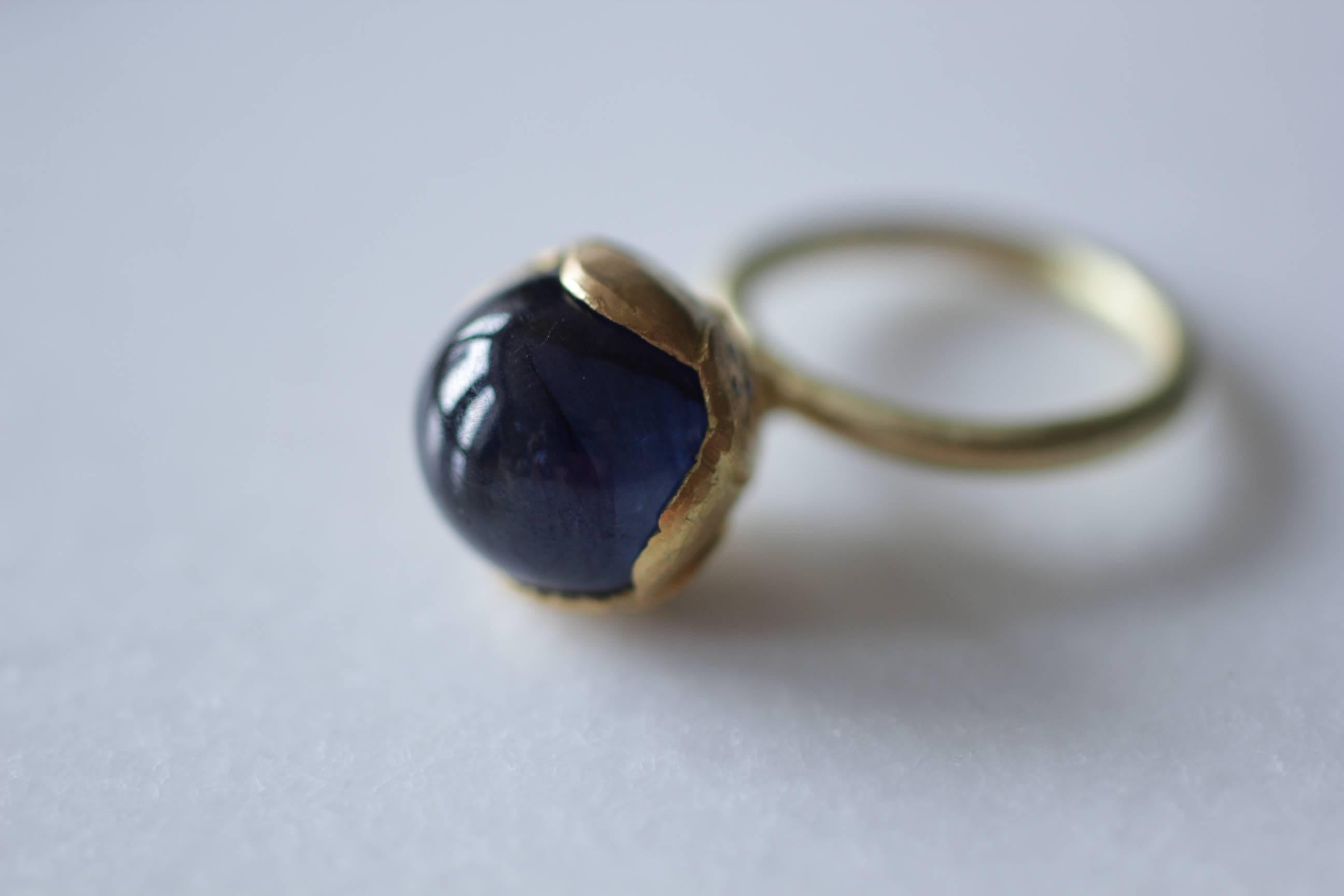 Lotus Flower Ring. An exotic stackable cocktail ring featuring Blue Sapphire Cabochon dome set in a 21k solid gold bezel mounted on 18k solid gold rounded shank. The bottom of the bezel is decoratively set with blue and black diamonds. This ring is