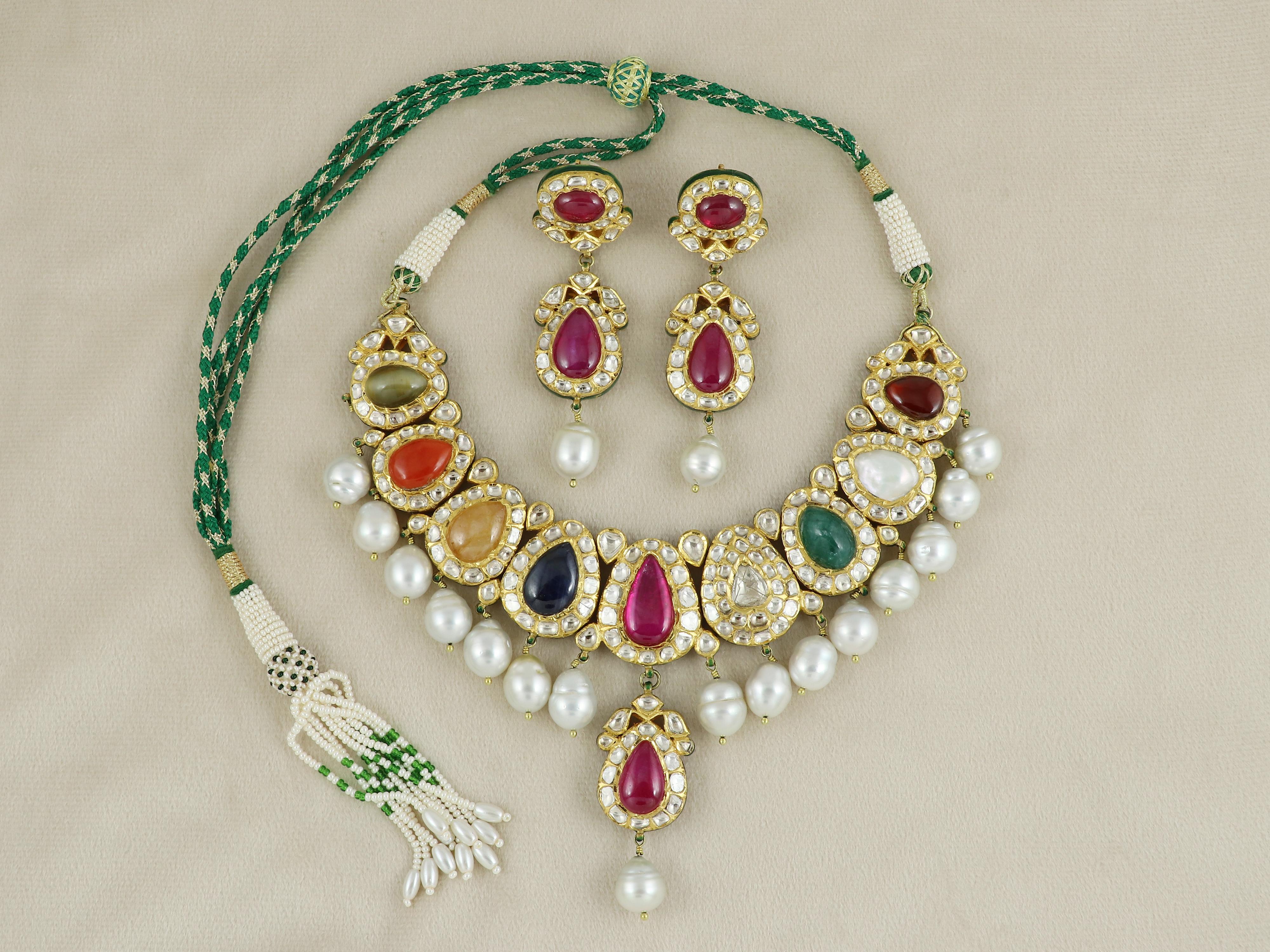 Indulge in the timeless opulence of Indian craftsmanship with this regal 22K gold Navratan bridal necklace, a radiant expression of tradition, artistry, and spiritual symbolism. Handcrafted by master artisans, this heirloom-quality piece is adorned