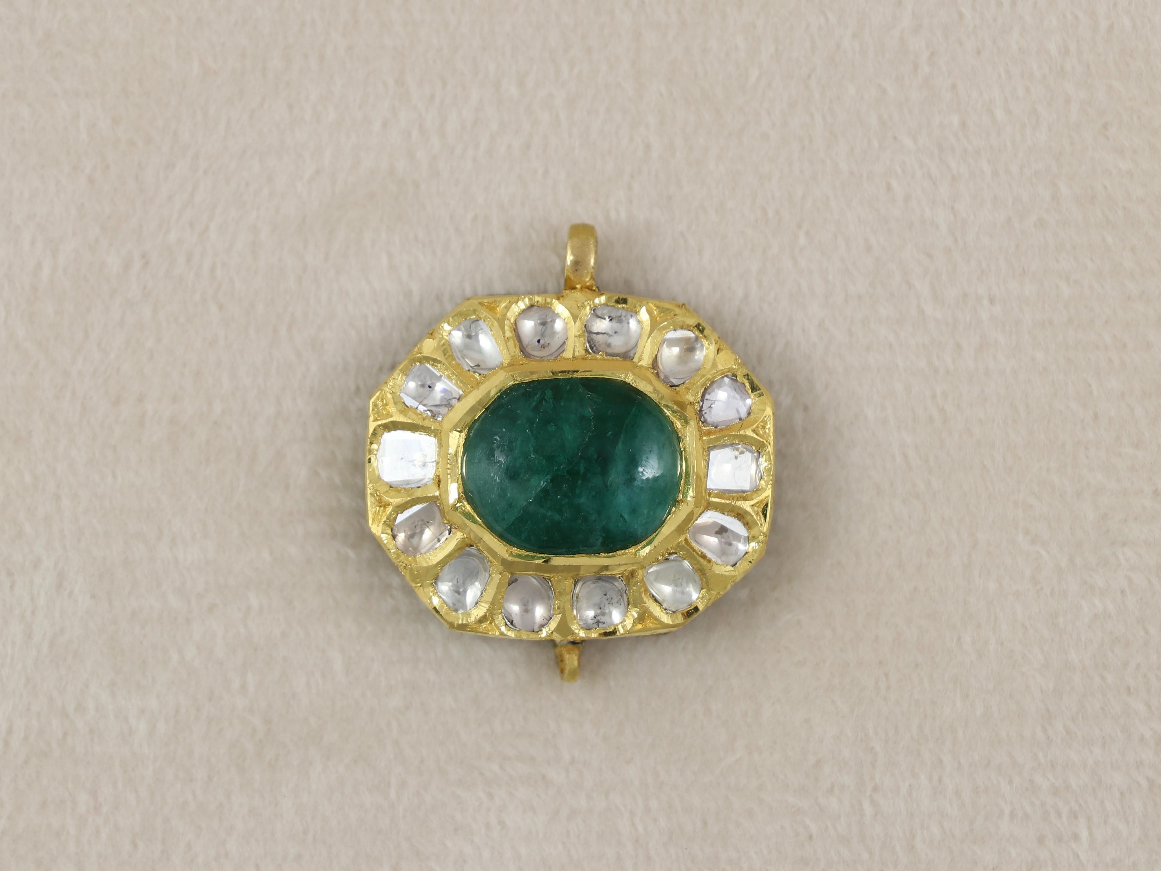 Questo piccolo ciondolo è realizzato a mano in oro 22 carati e si rifà ai tradizionali gioielli Kundan Meena polki dell'India. Il pendente di piccole dimensioni è incastonato con uno smeraldo al centro in un'incastonatura ottagonale ed è circondato