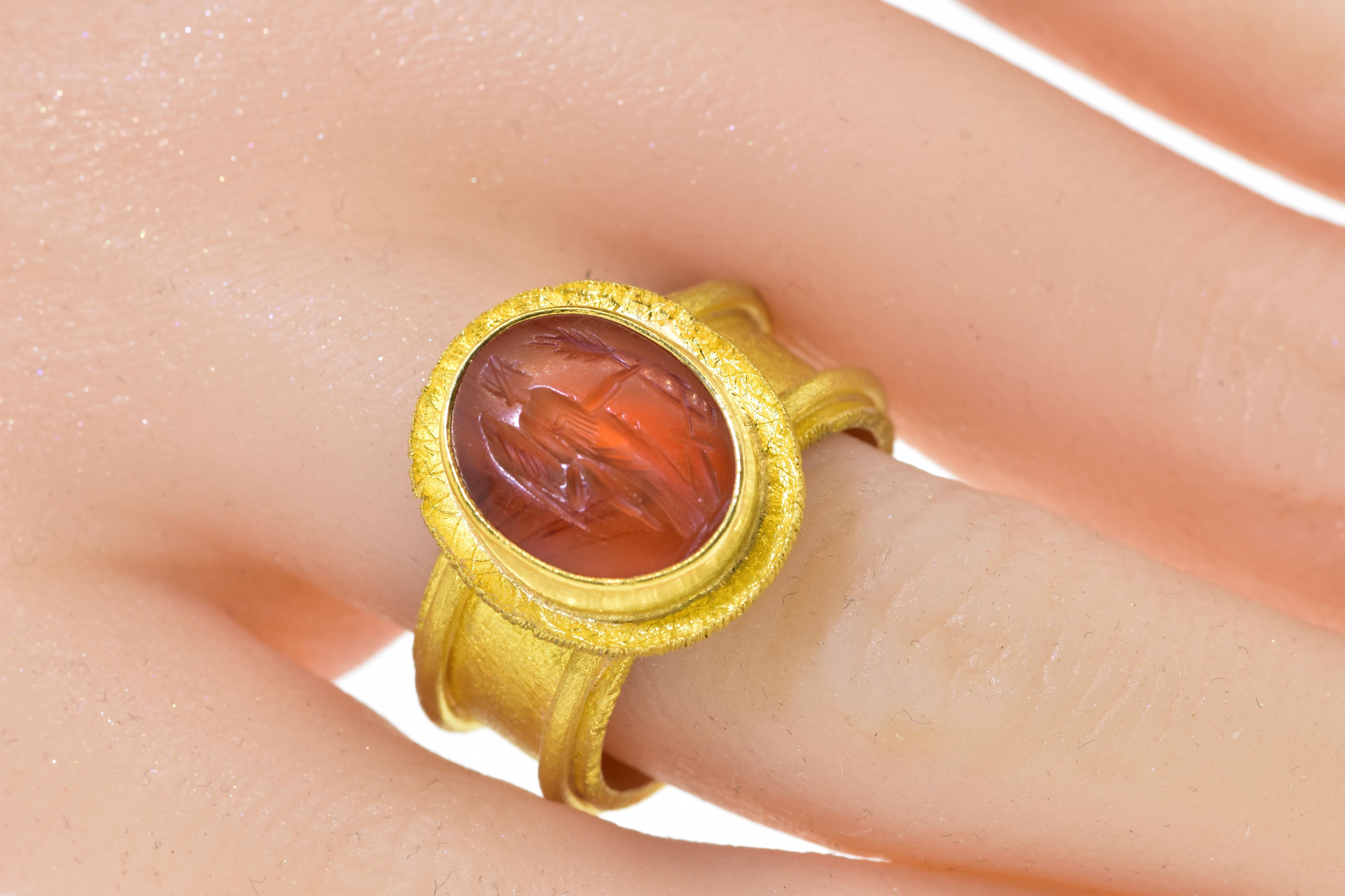 22K yellow contemporary gold ring centering an antique carnelian intaglio, c. 1850, of a standing angel extending an olive branch - signifying peace. The intaglio is in fine condition, measures 14.4 mm by 11.5 mm.  and remounted in this contemporary