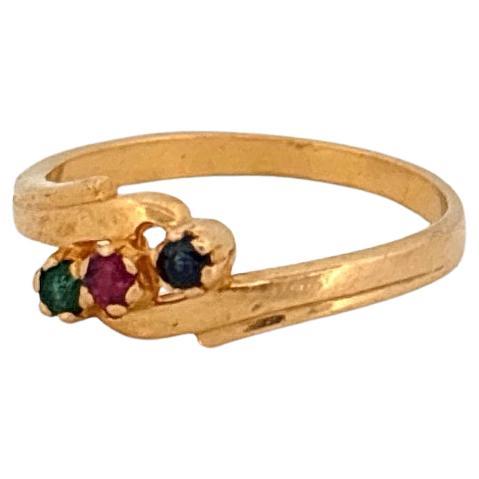 Cette élégante bague en or jaune 22k, pesant 3 grammes, présente un design intemporel à trois pierres, orné de pierres précieuses naturelles vibrantes. En son centre se trouve un rubis rond de 0,03 carat, d'une riche teinte cramoisie qui symbolise