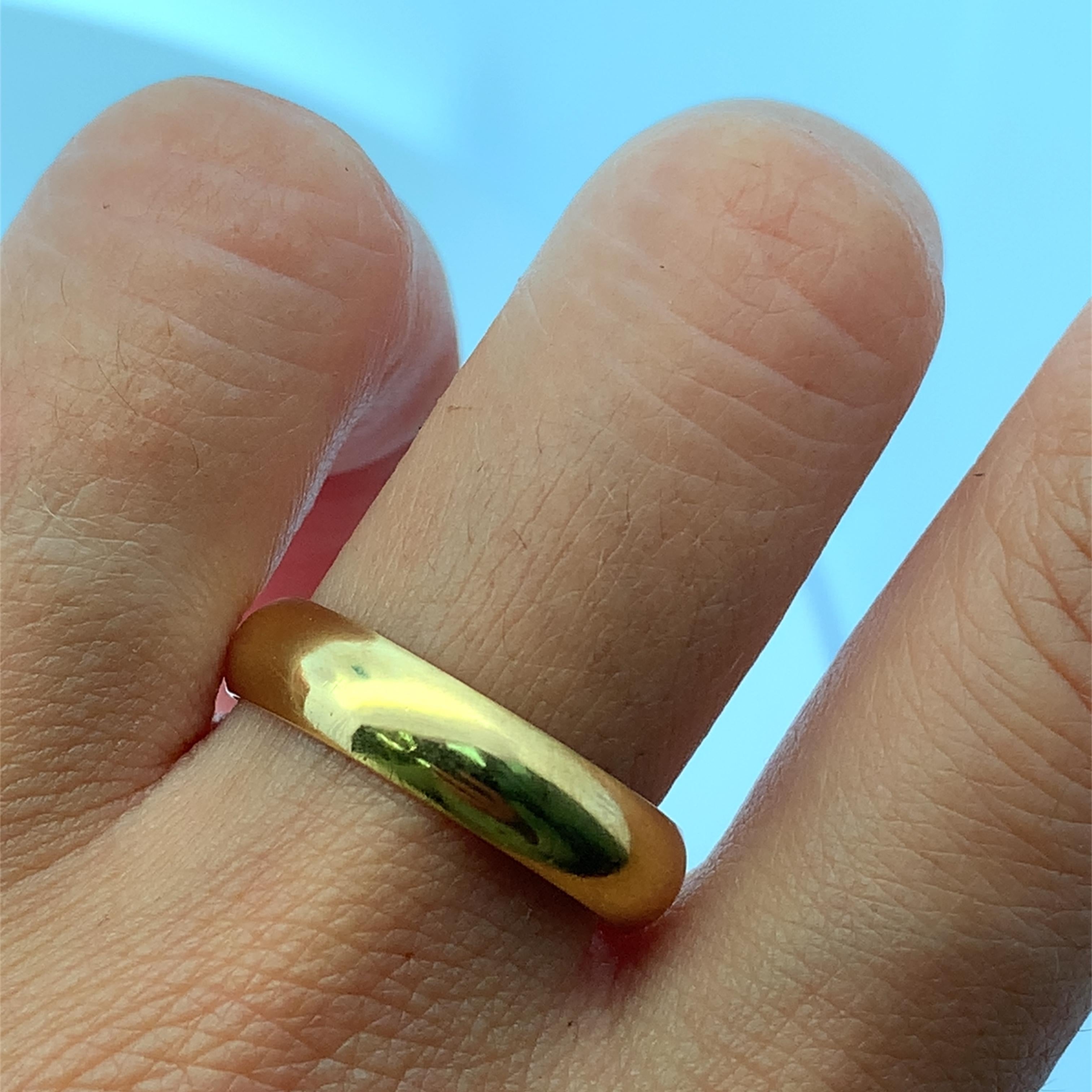Experience the timeless elegance of this classic pure 22k yellow gold band ring 5.5mm, 6.1g. Crafted from lustrous gold, this ring features a smooth, rounded design, perfect for everyday wear or as a symbol of enduring commitment. Its understated