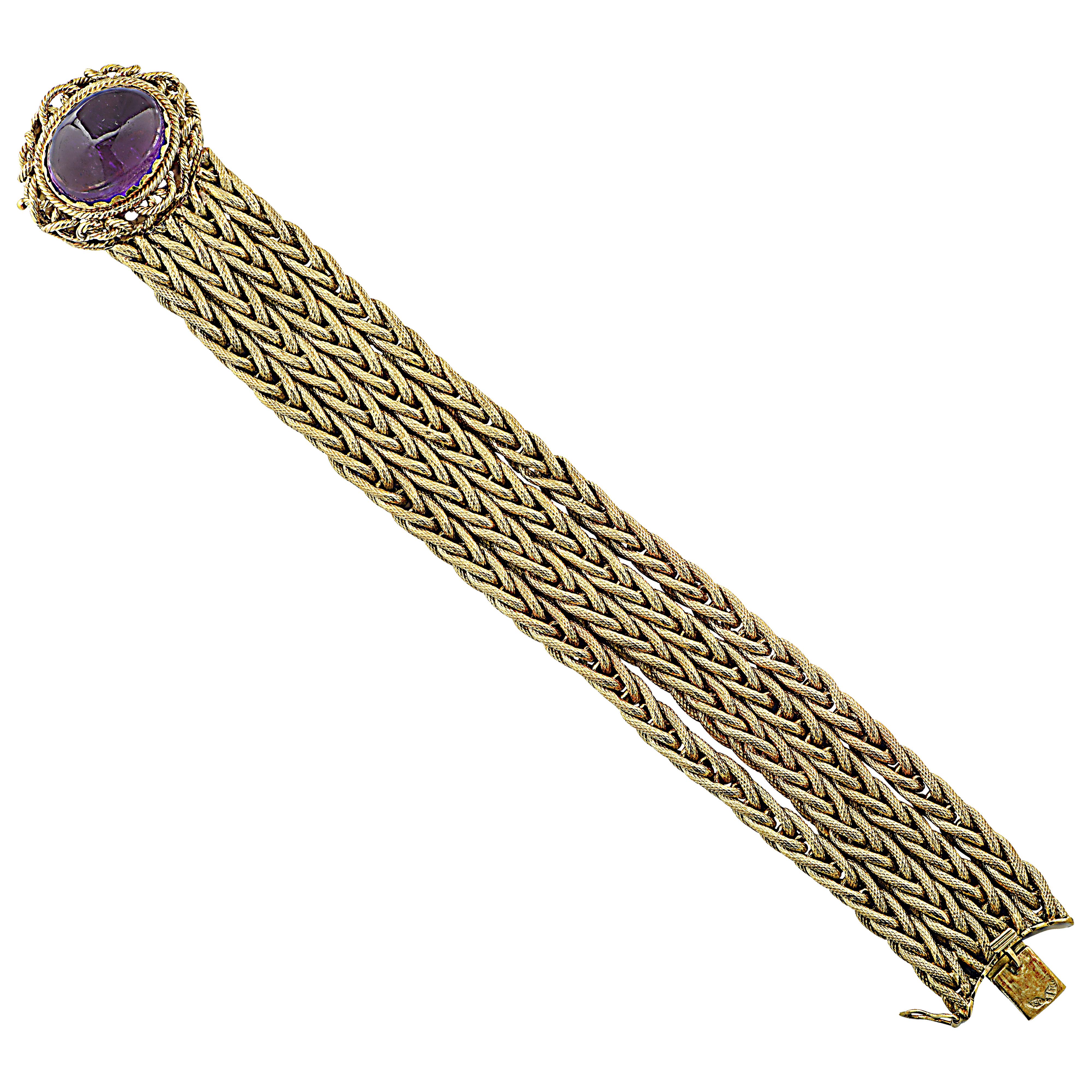 Stunning bracelet crafted in 18 karat yellow gold featuring a spectacular oval shape Amethyst cabochon weighing approximately 23 carats, resting regally on a bed of intricately twisted and woven gold strands. The face of this beautiful bracelet